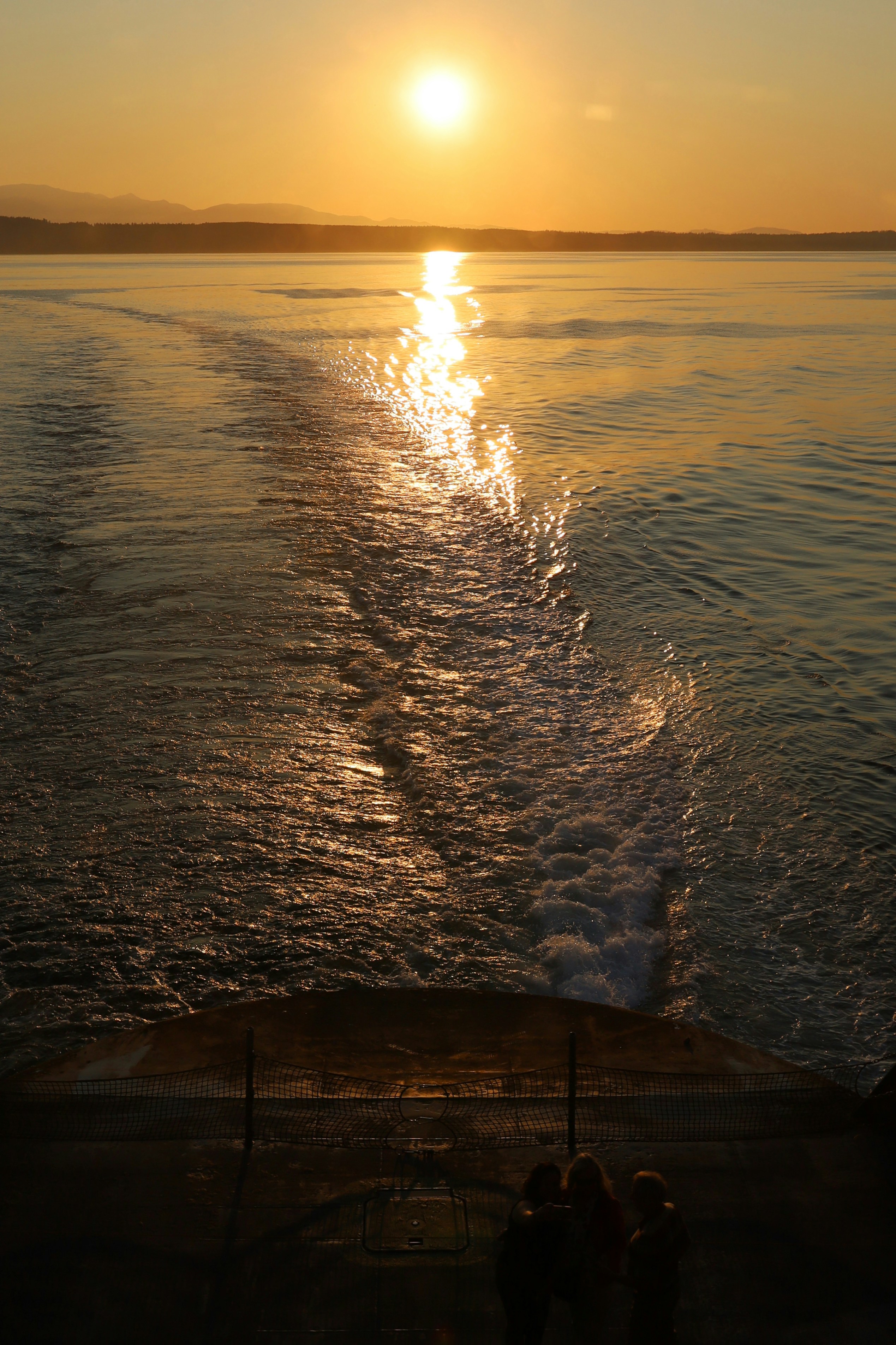 The sun is setting over the water on a boat