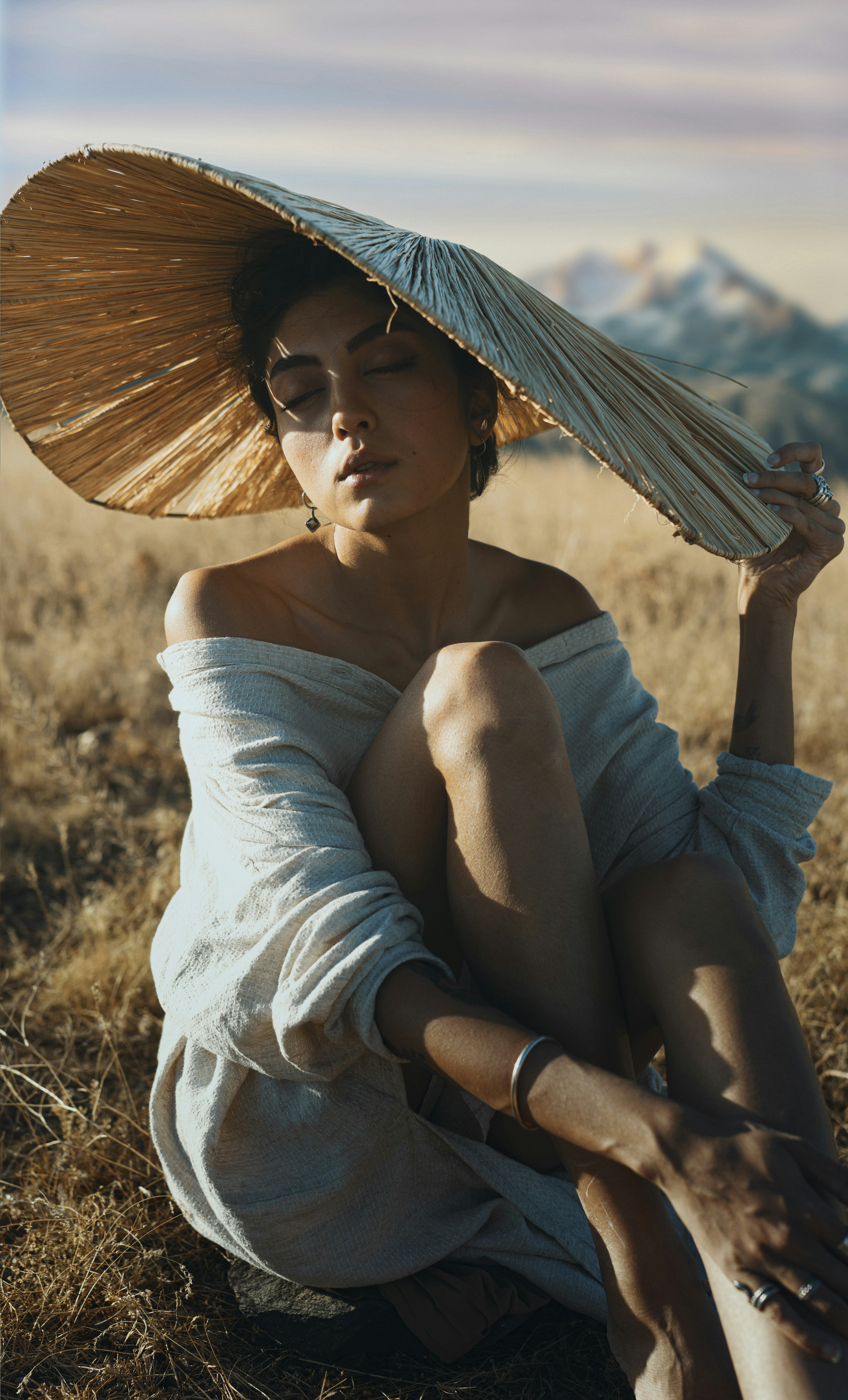 Una mujer sentada en un campo con un sombrero en la cabeza