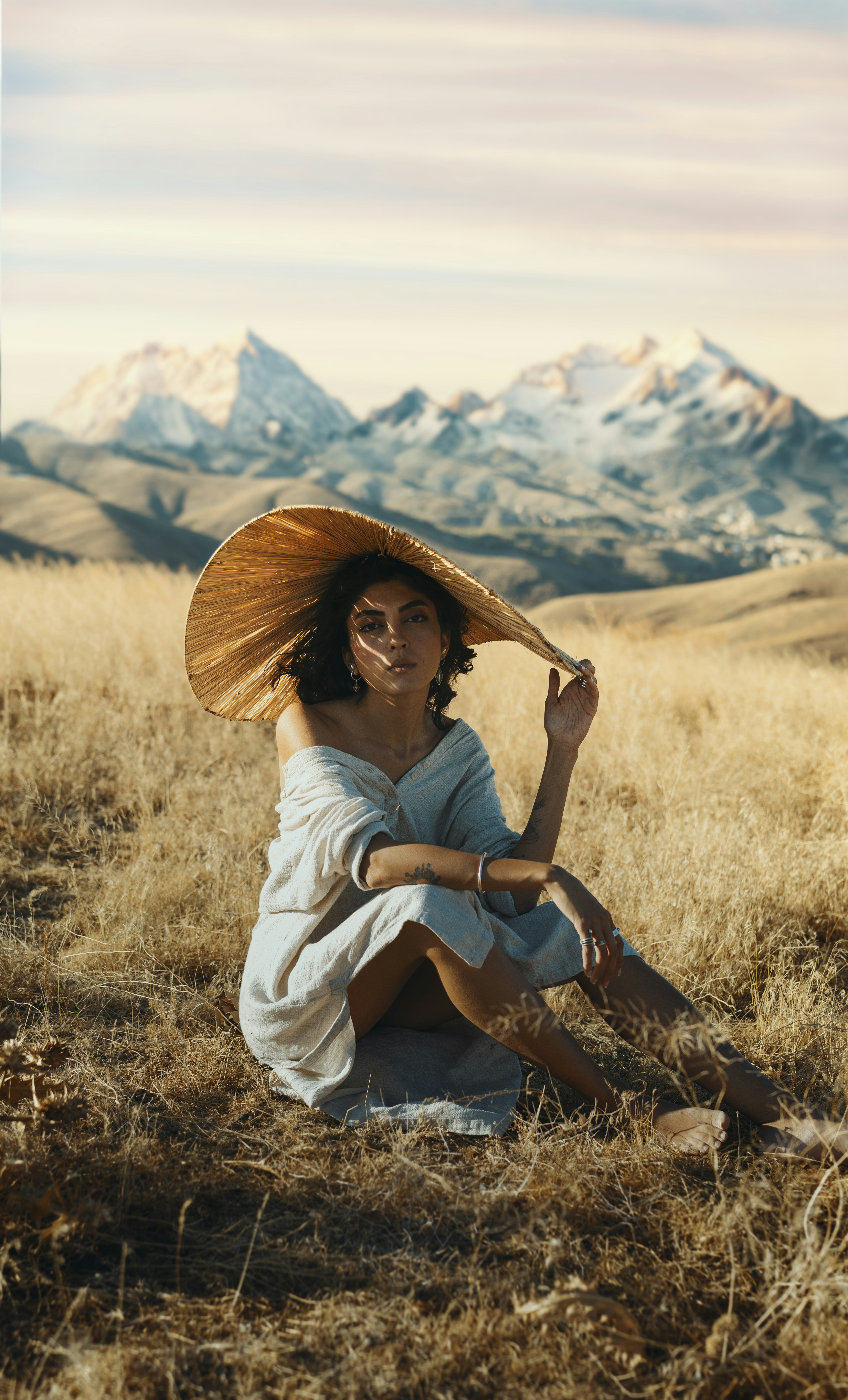 Una mujer sentada en un campo con un sombrero de paja en la cabeza