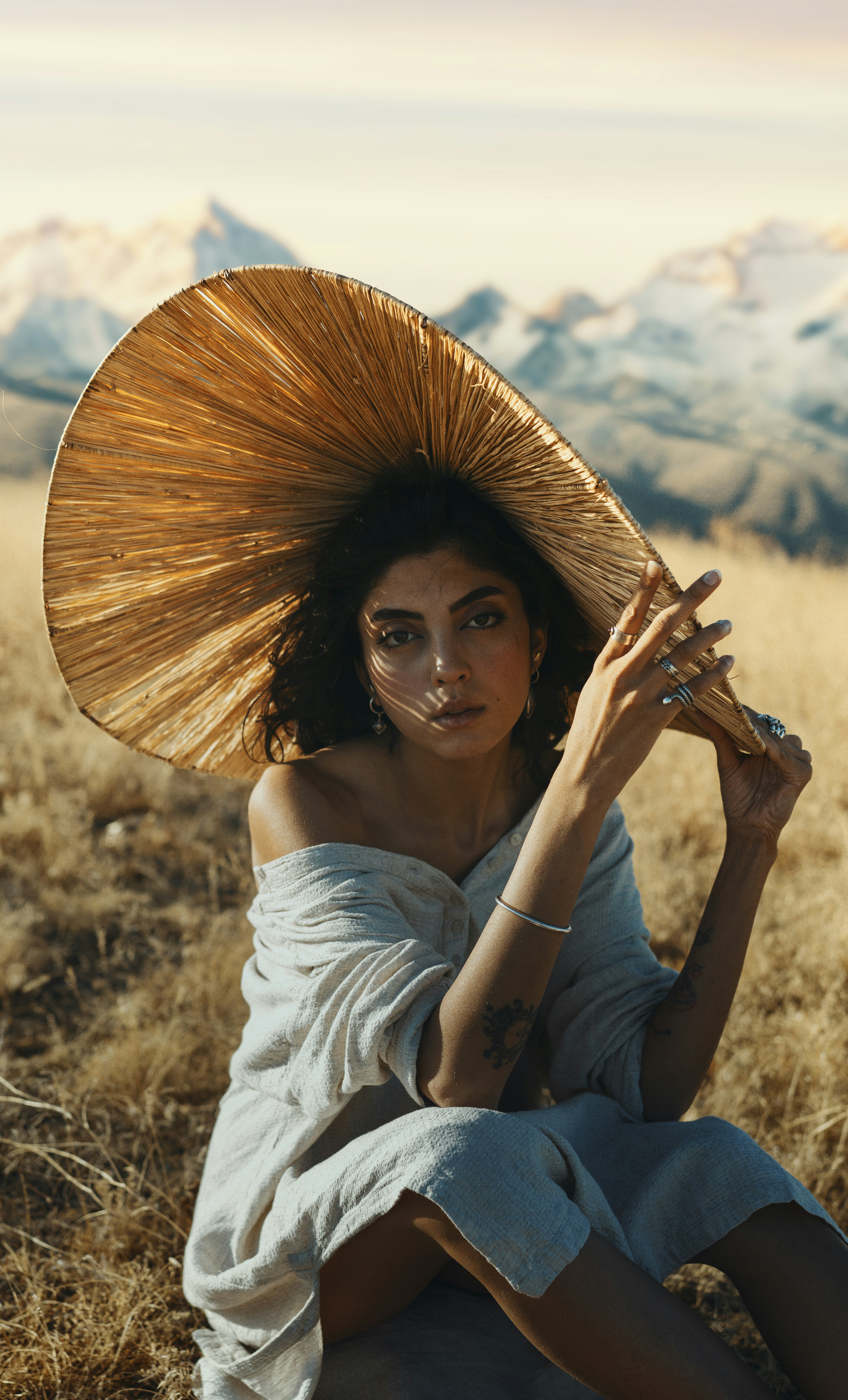 Una mujer sentada en el suelo con un gran sombrero en la cabeza