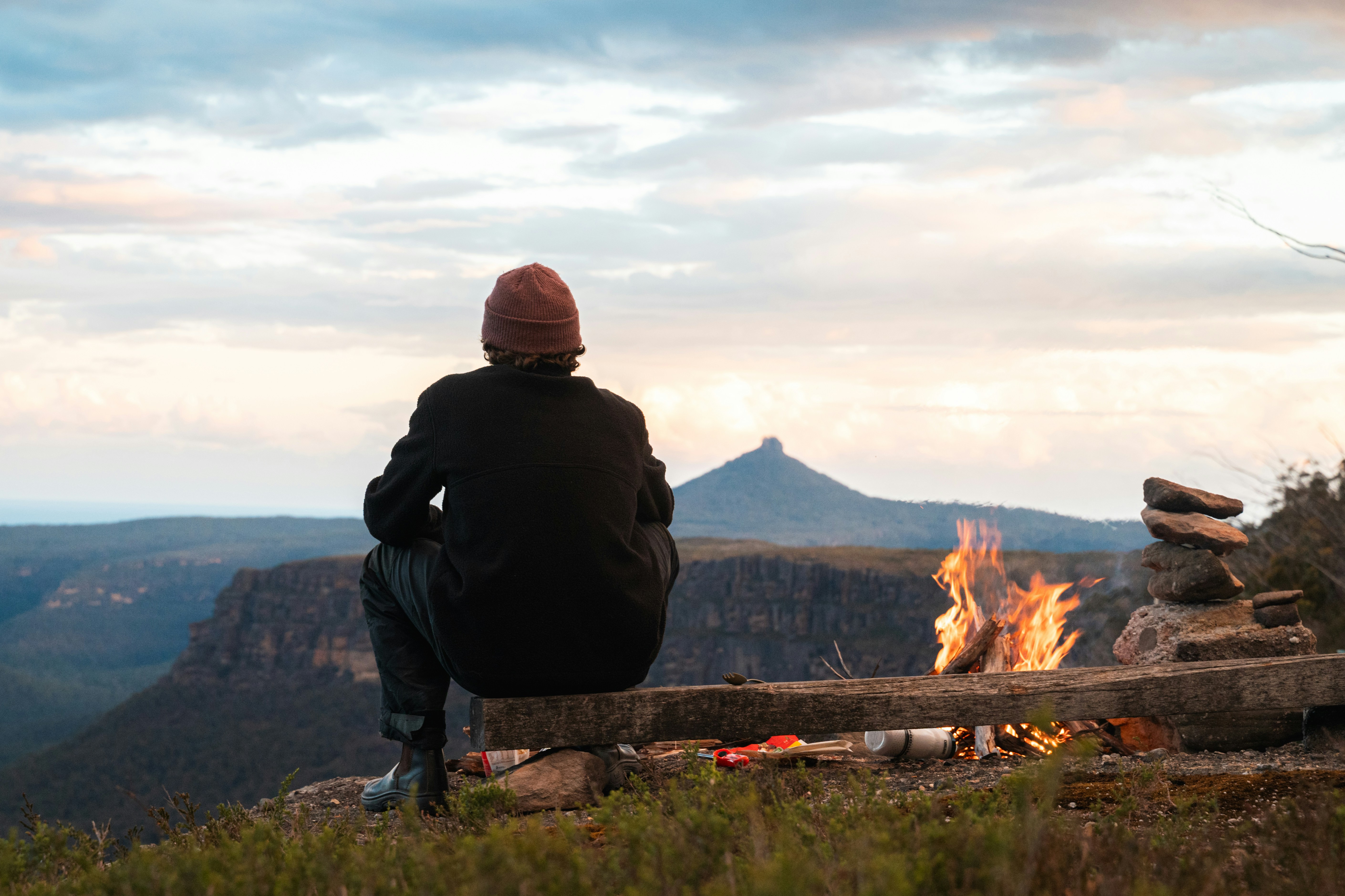 A person sitting on a bench looking at a fire
