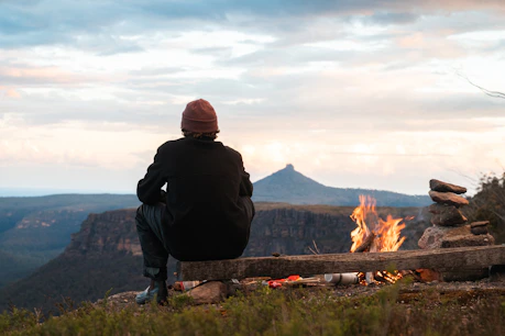 A person sitting on a bench looking at a fire