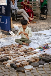 A young boy sitting on the ground next to a pile of bricks