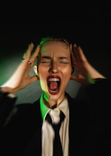 A woman in a suit and tie with her hands on her head