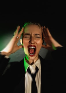 A woman in a suit and tie with her hands on her head