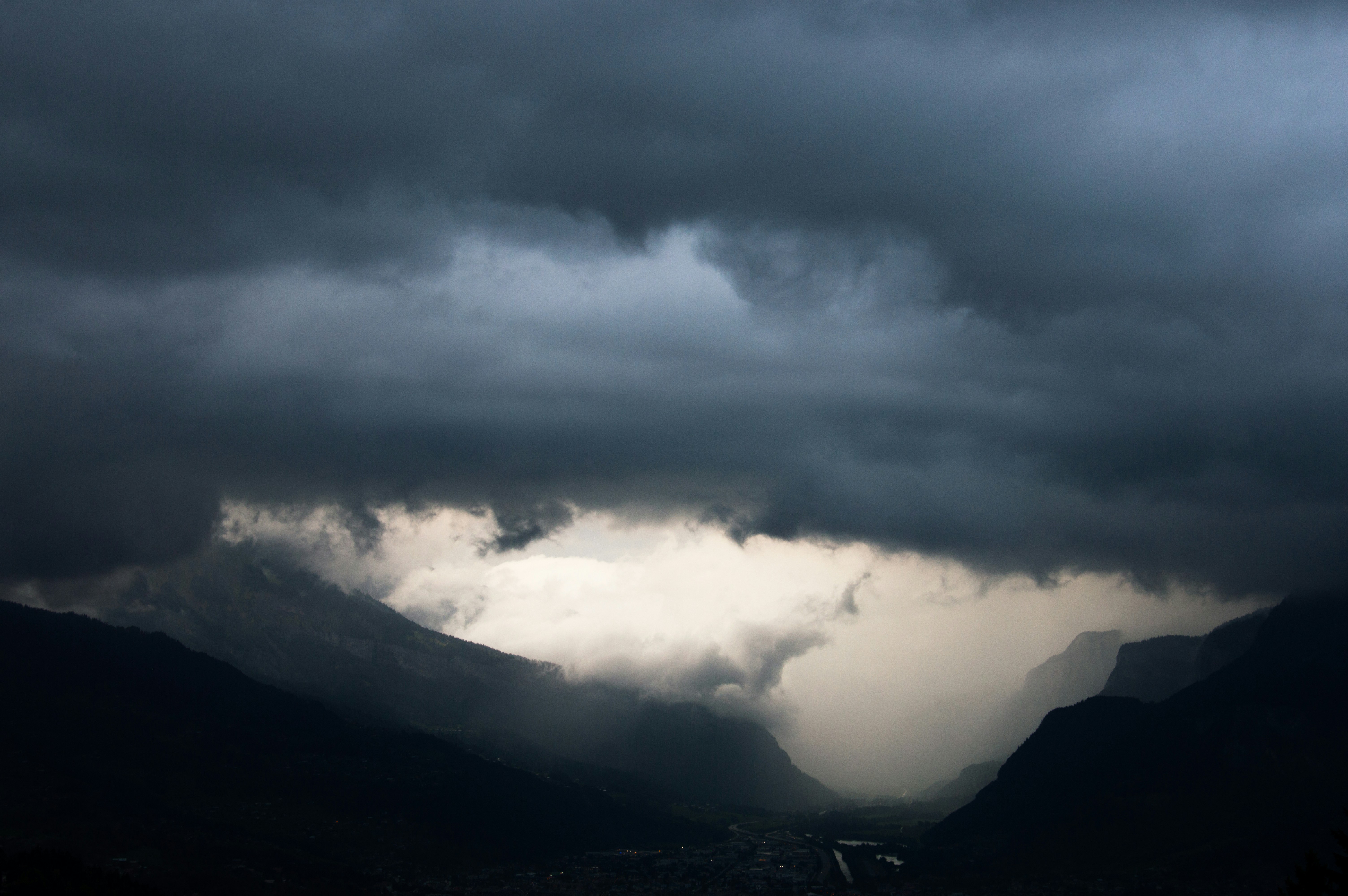 A dark cloud hangs over a mountain range photo Free Magland Image on