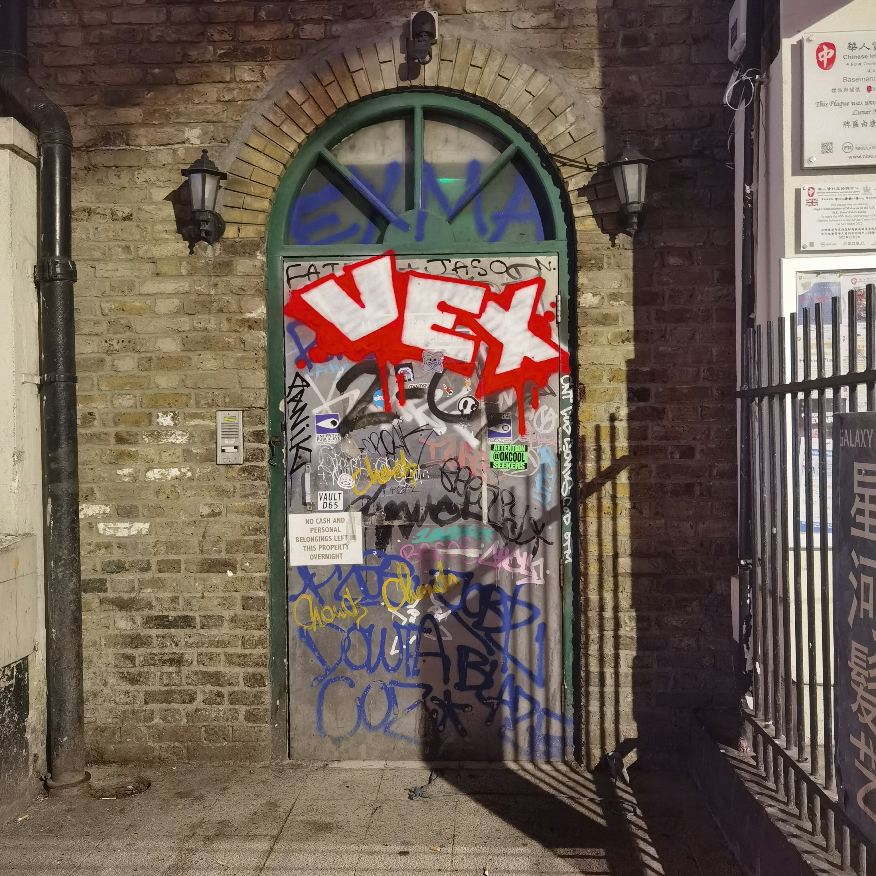 A brick building with a green door and graffiti on it