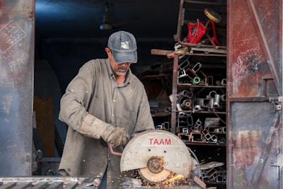 A man cutting a piece of metal with a circular saw