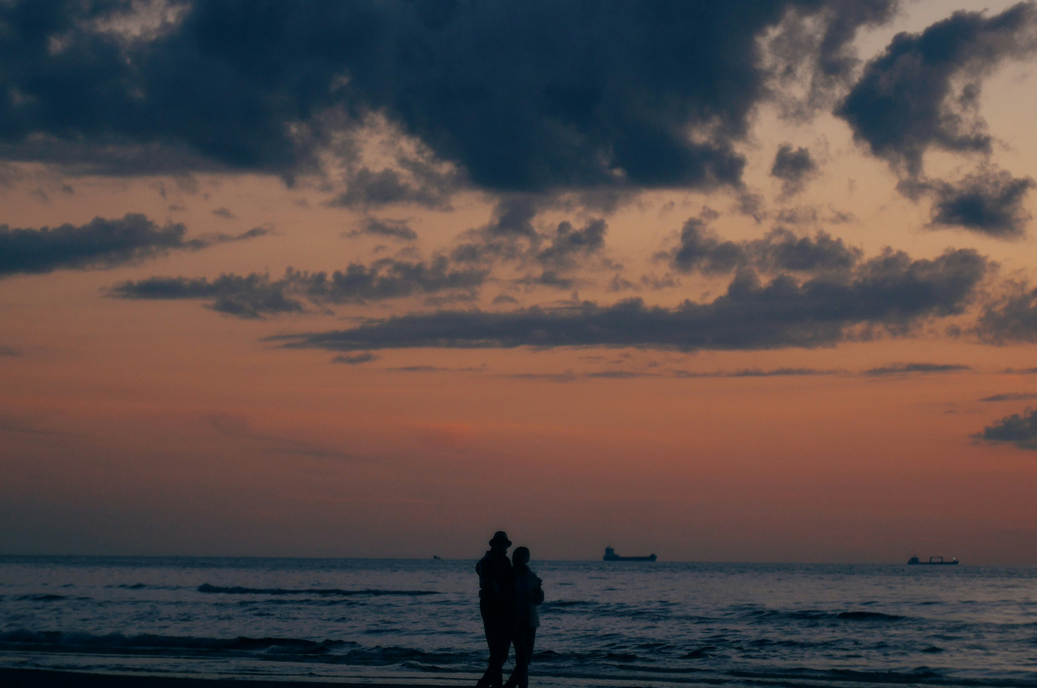 A couple of people standing on top of a beach