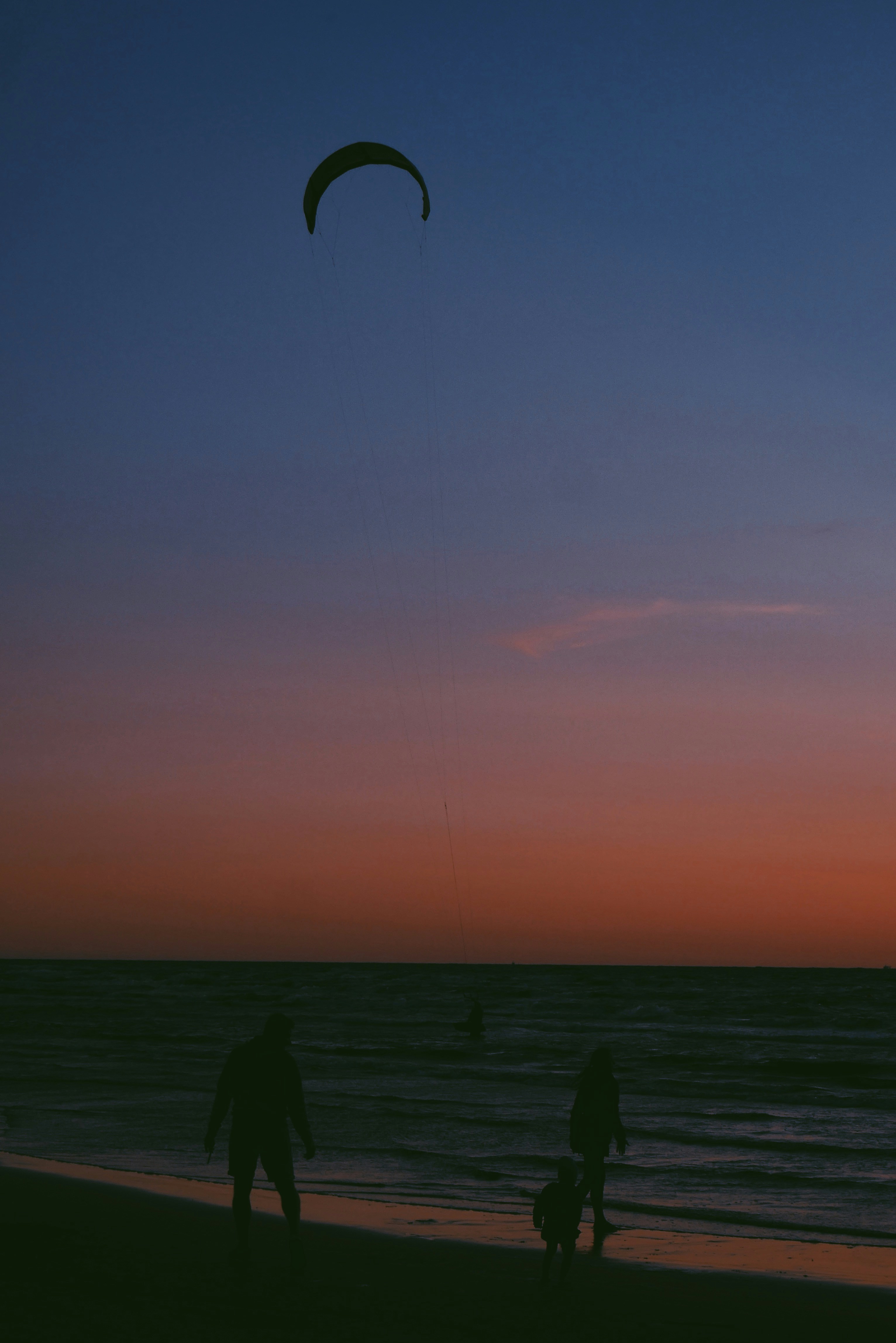 A couple of people flying a kite on top of a beach