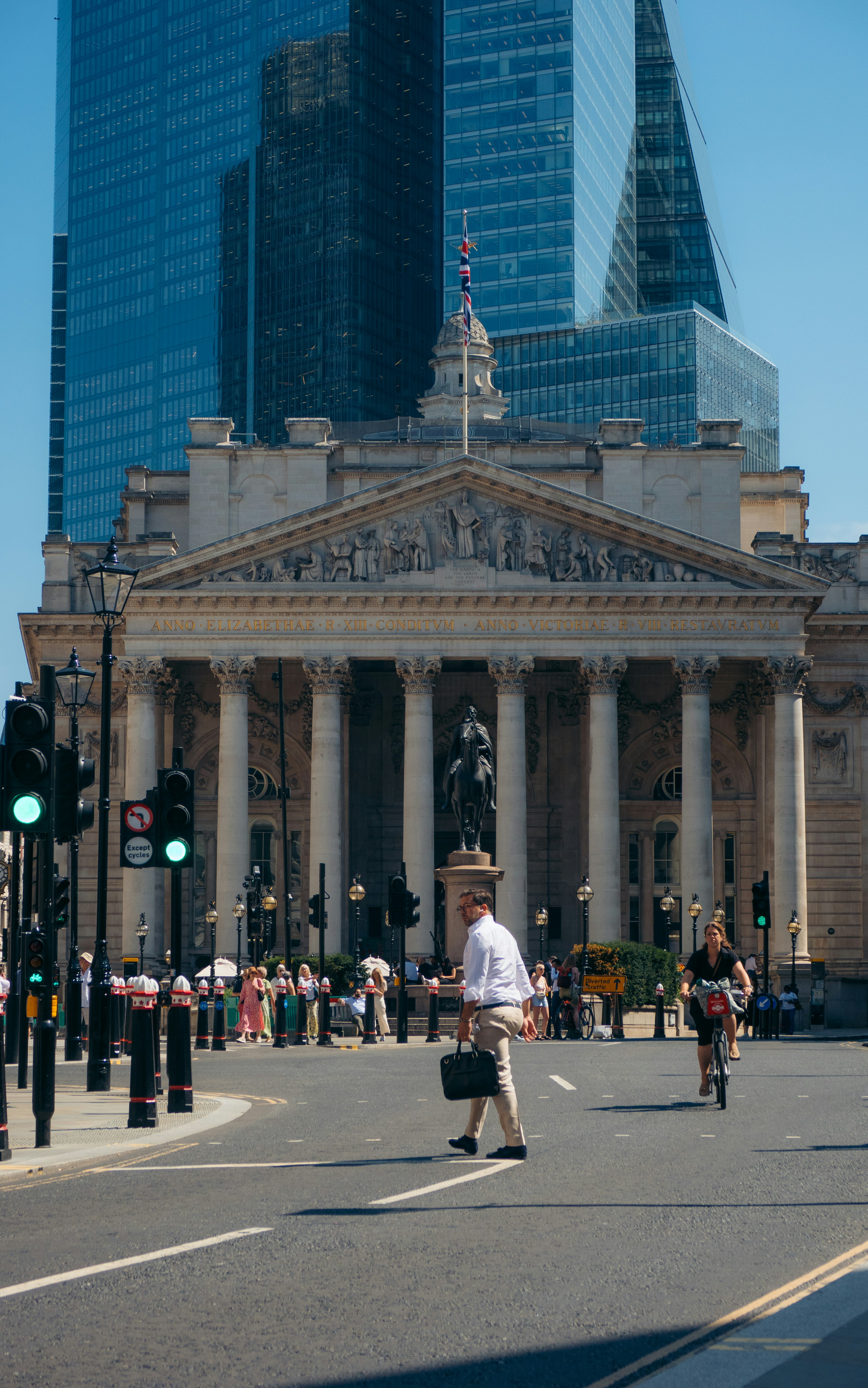 A man walking across a street in front of a tall building photo – Free ...