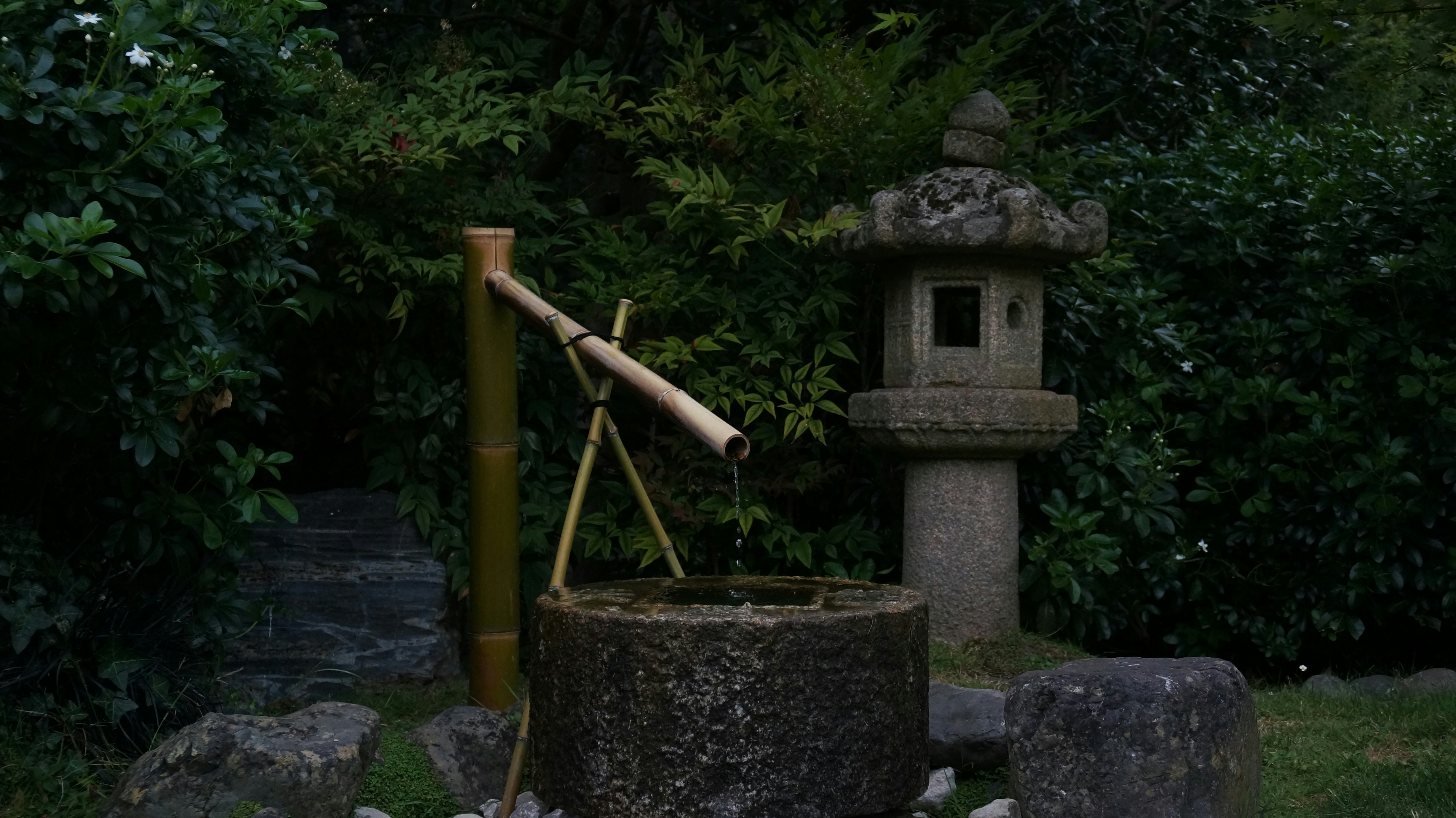 A stone fountain with a bamboo stick sticking out of it