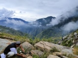 A man kneeling down on top of a mountain