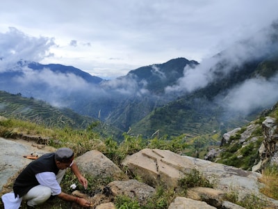 A man kneeling down on top of a mountain