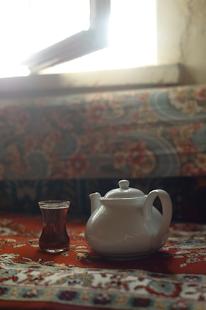A tea pot and a cup on a table