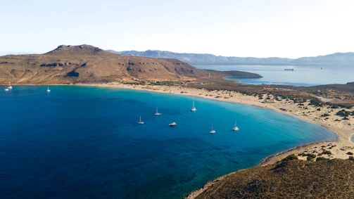 An aerial view of a beach with boats in the water