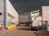 A truck parked in front of a building under a cloudy sky