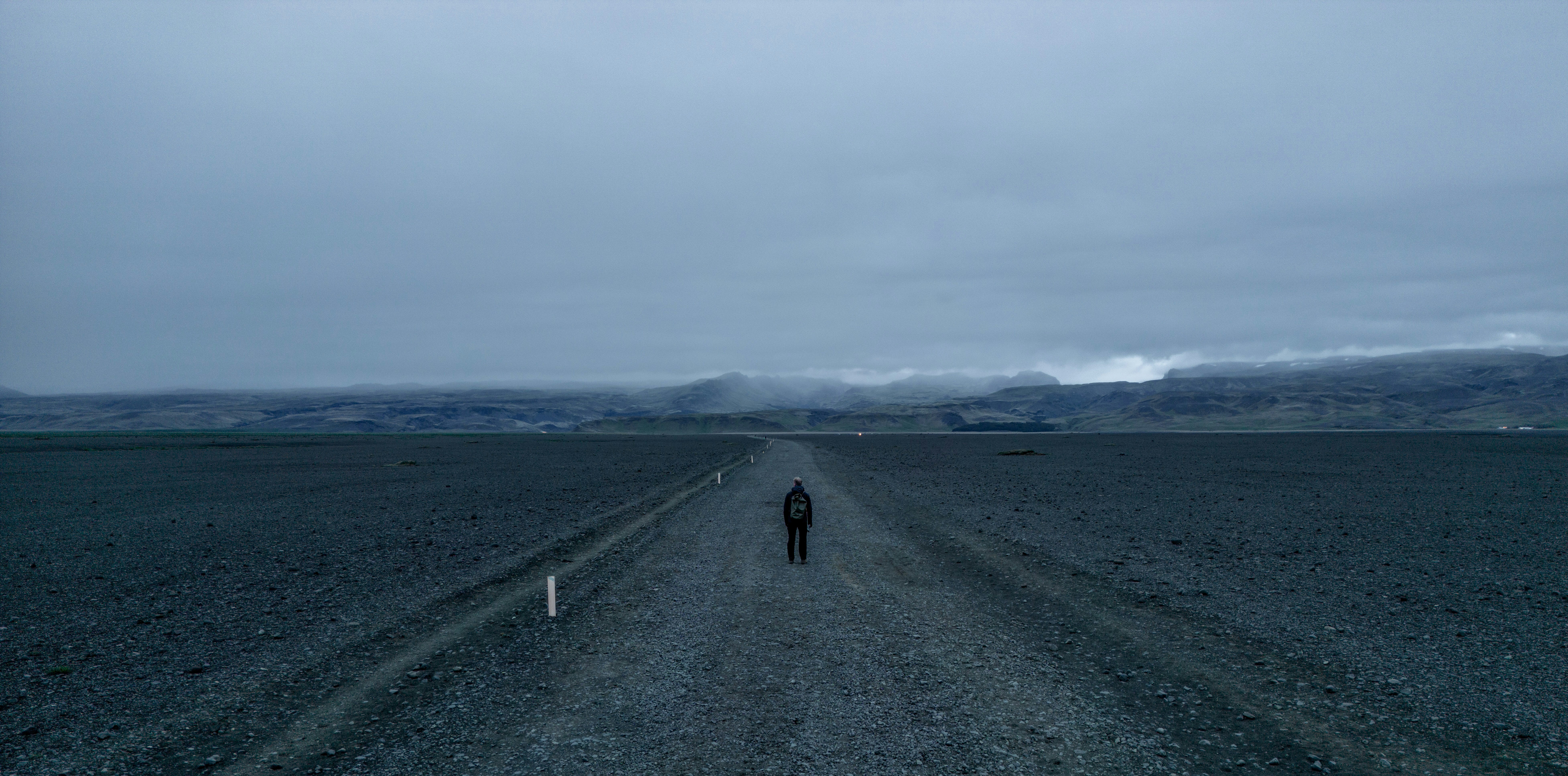 A person walking down a dirt road in the middle of nowhere