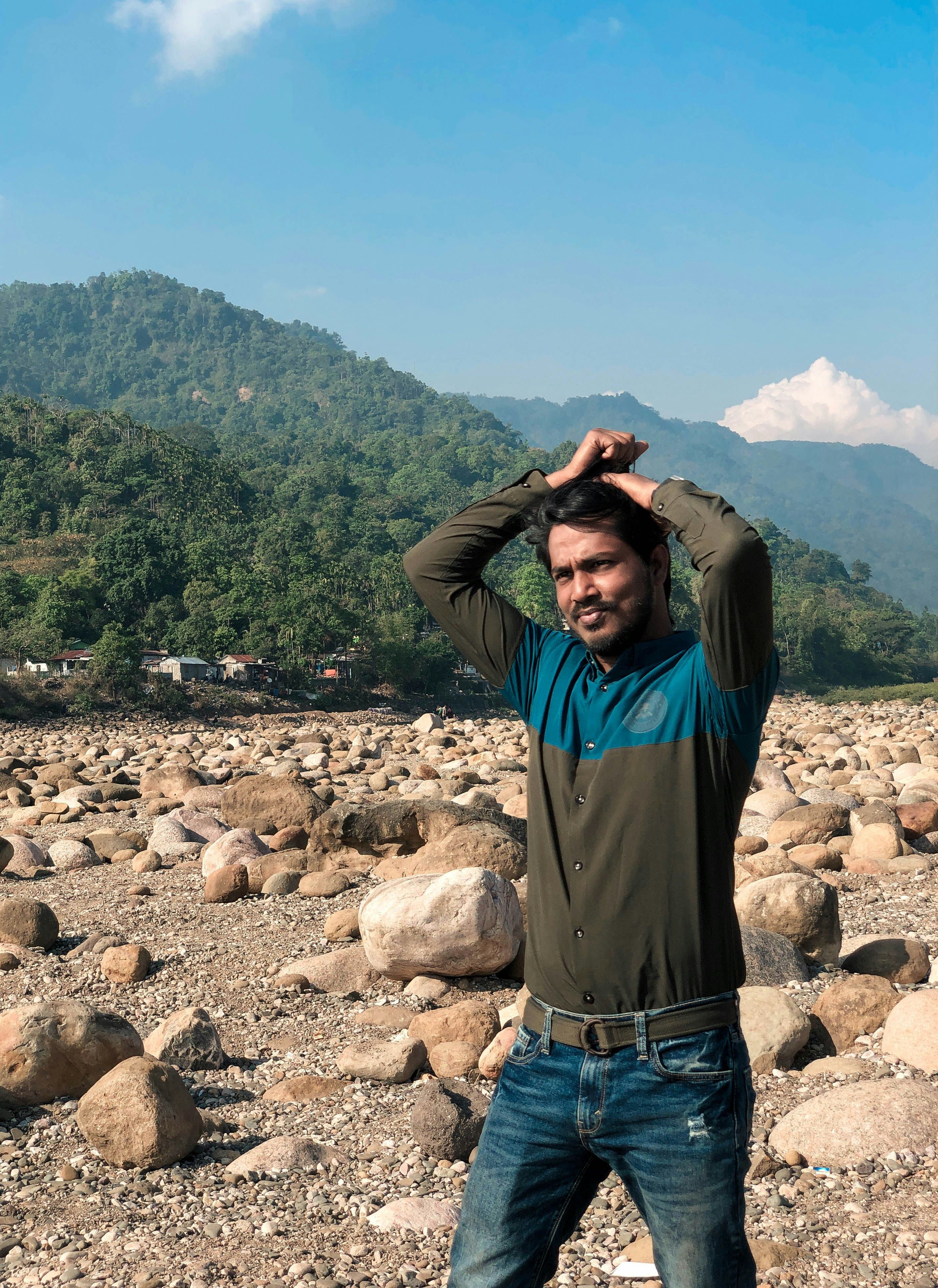 岩場に両手を頭に当てて立っている男性