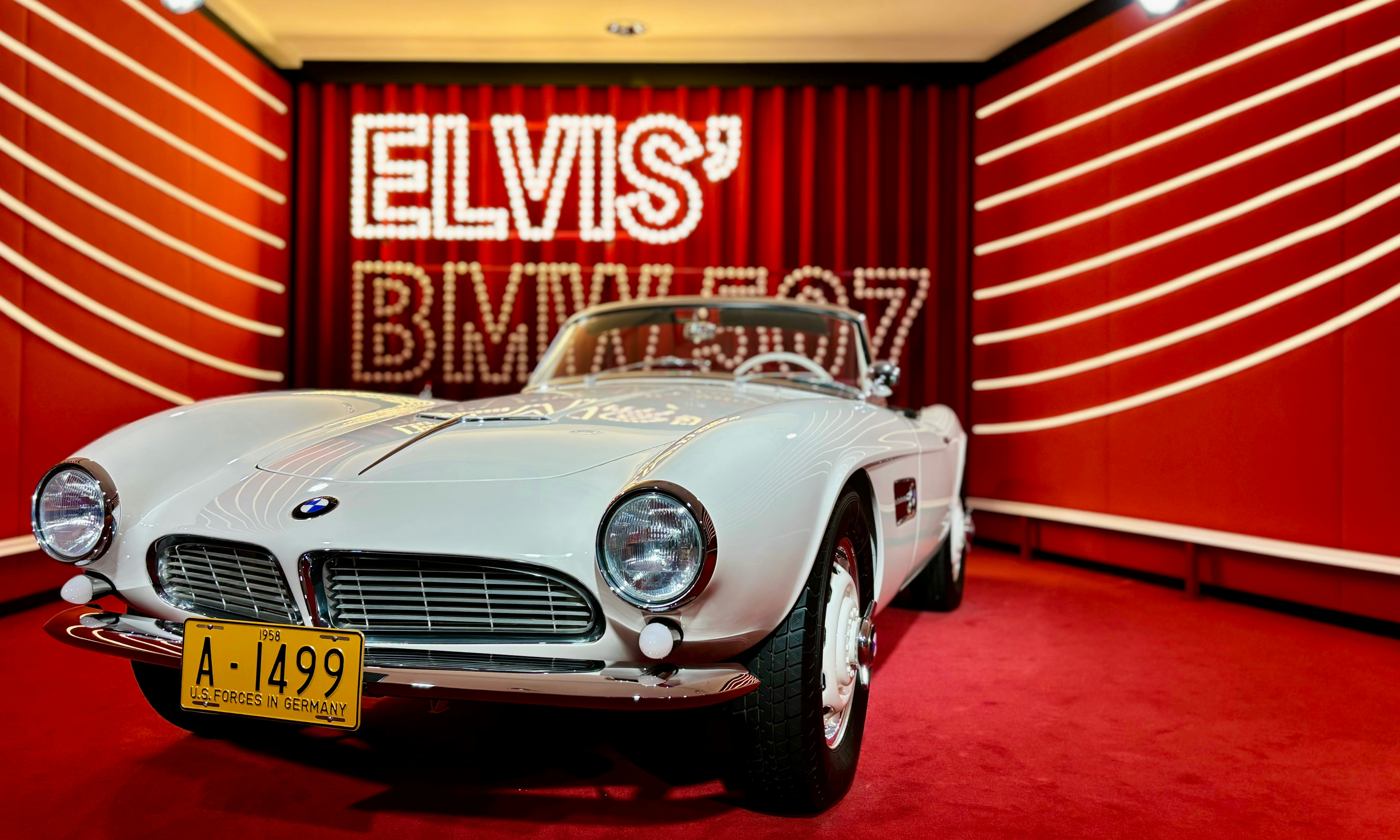 A white sports car parked in front of a red wall