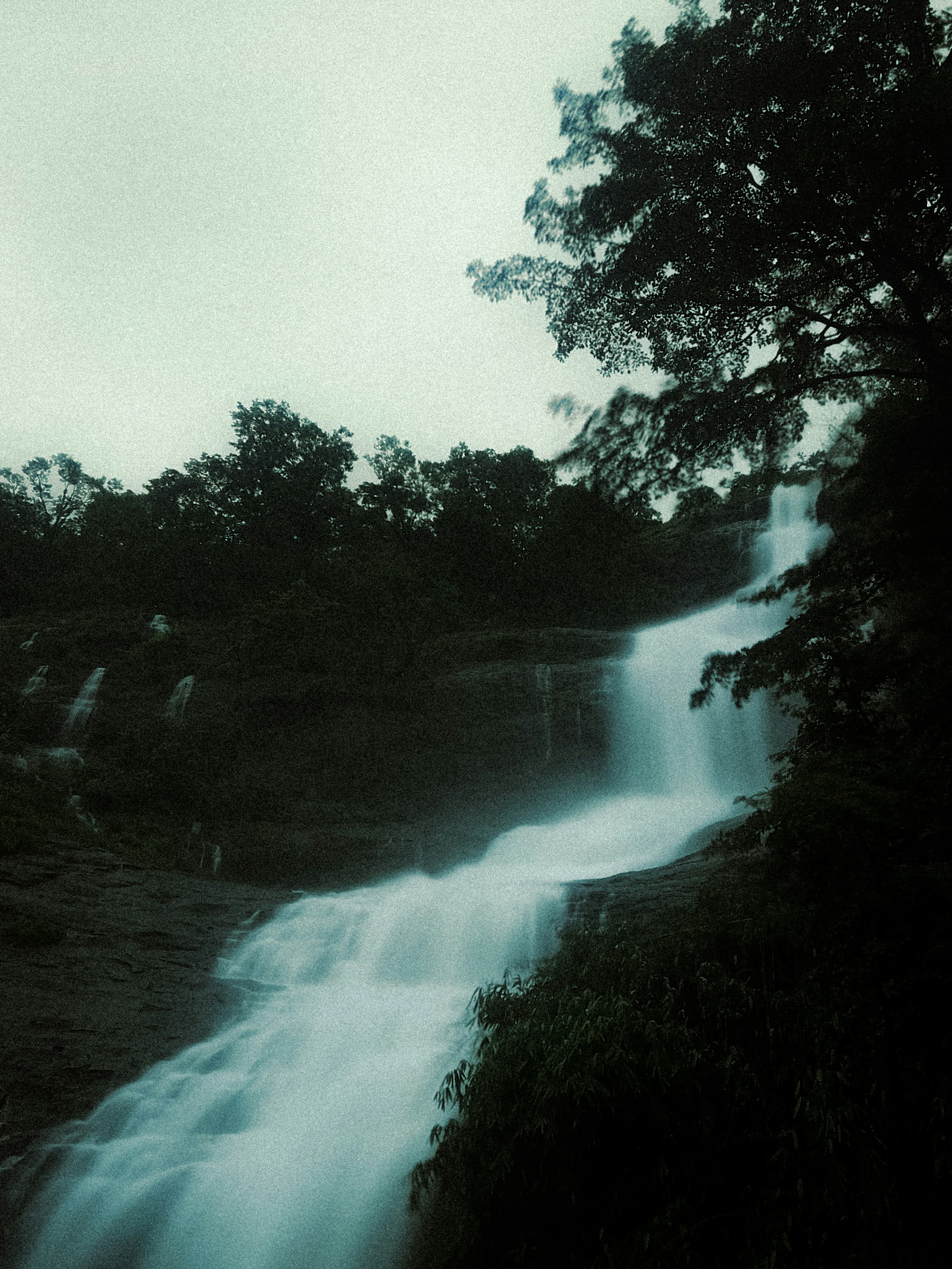 A very tall waterfall in the middle of a forest