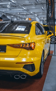 A yellow car is on display in a showroom