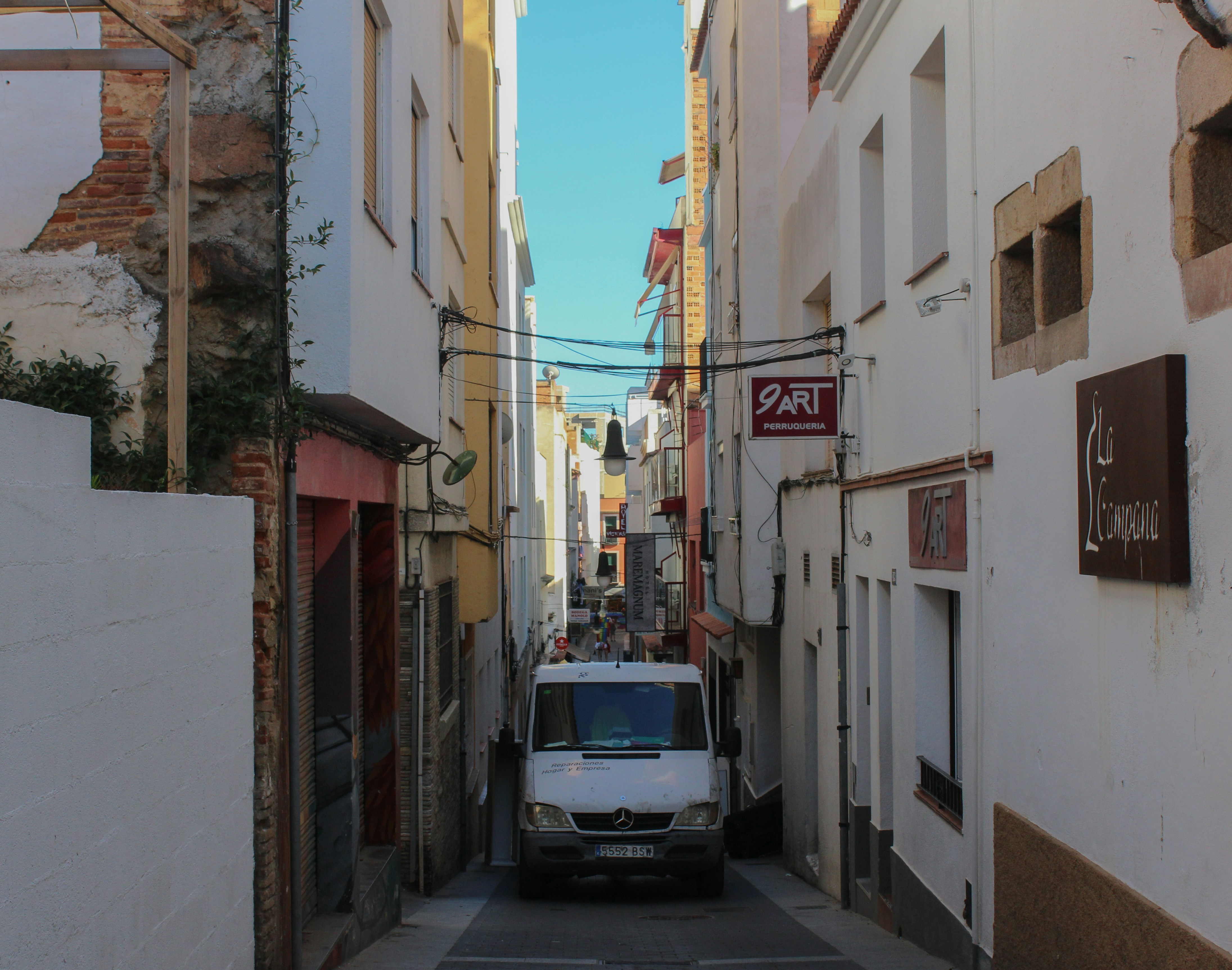 A van is parked on the side of a narrow street