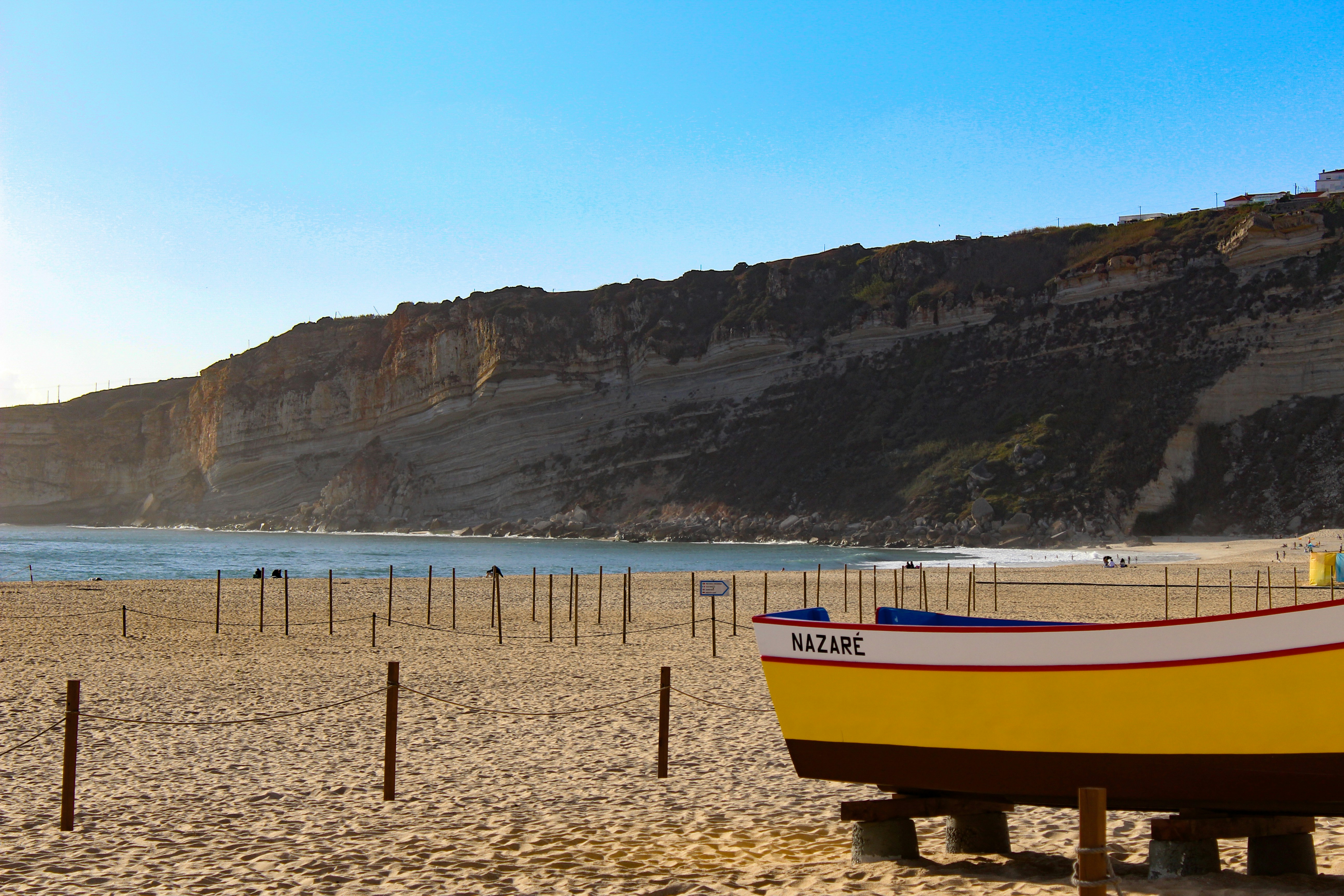A yellow boat sitting on top of a sandy beach