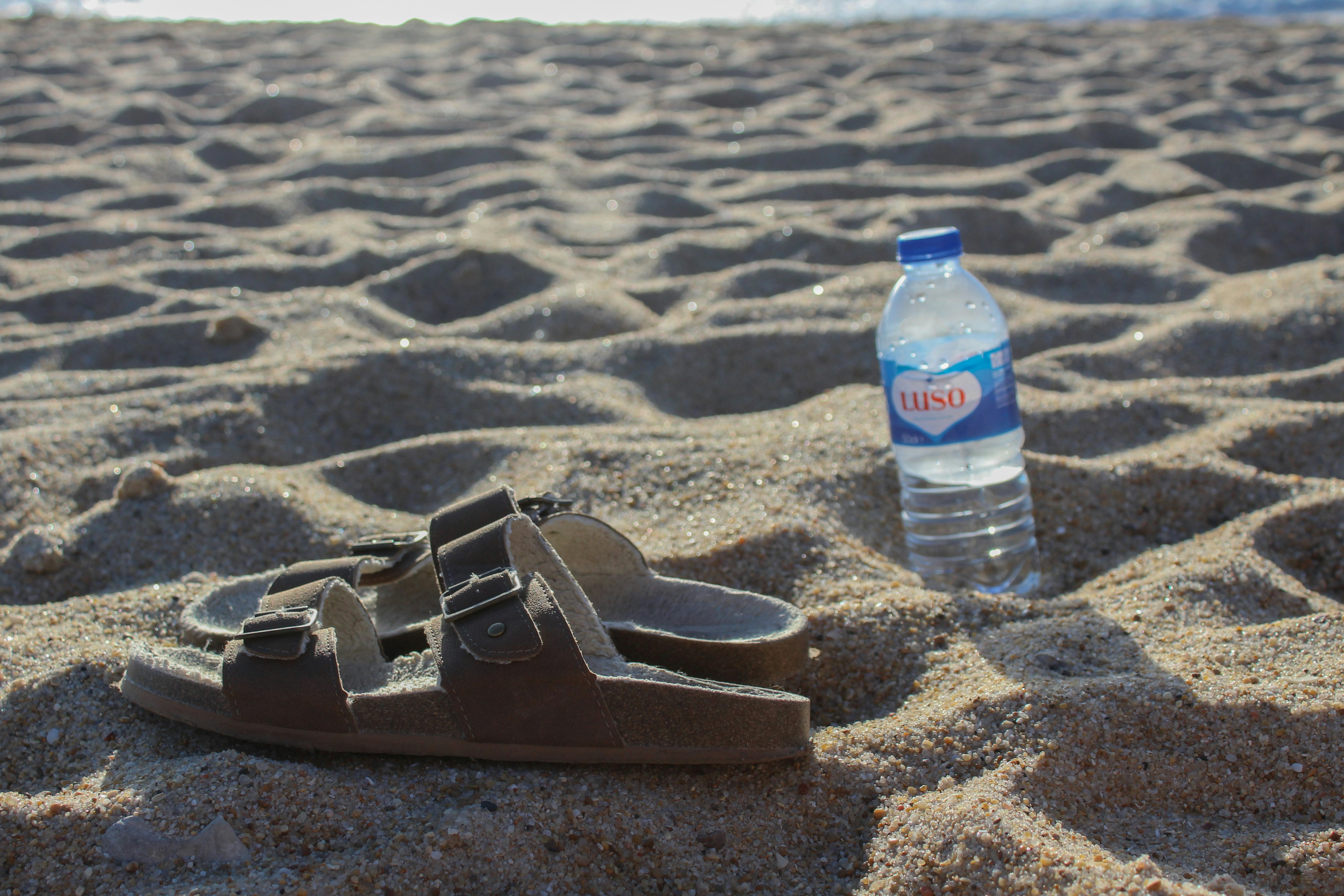 A bottle of water sitting on top of a sandy beach