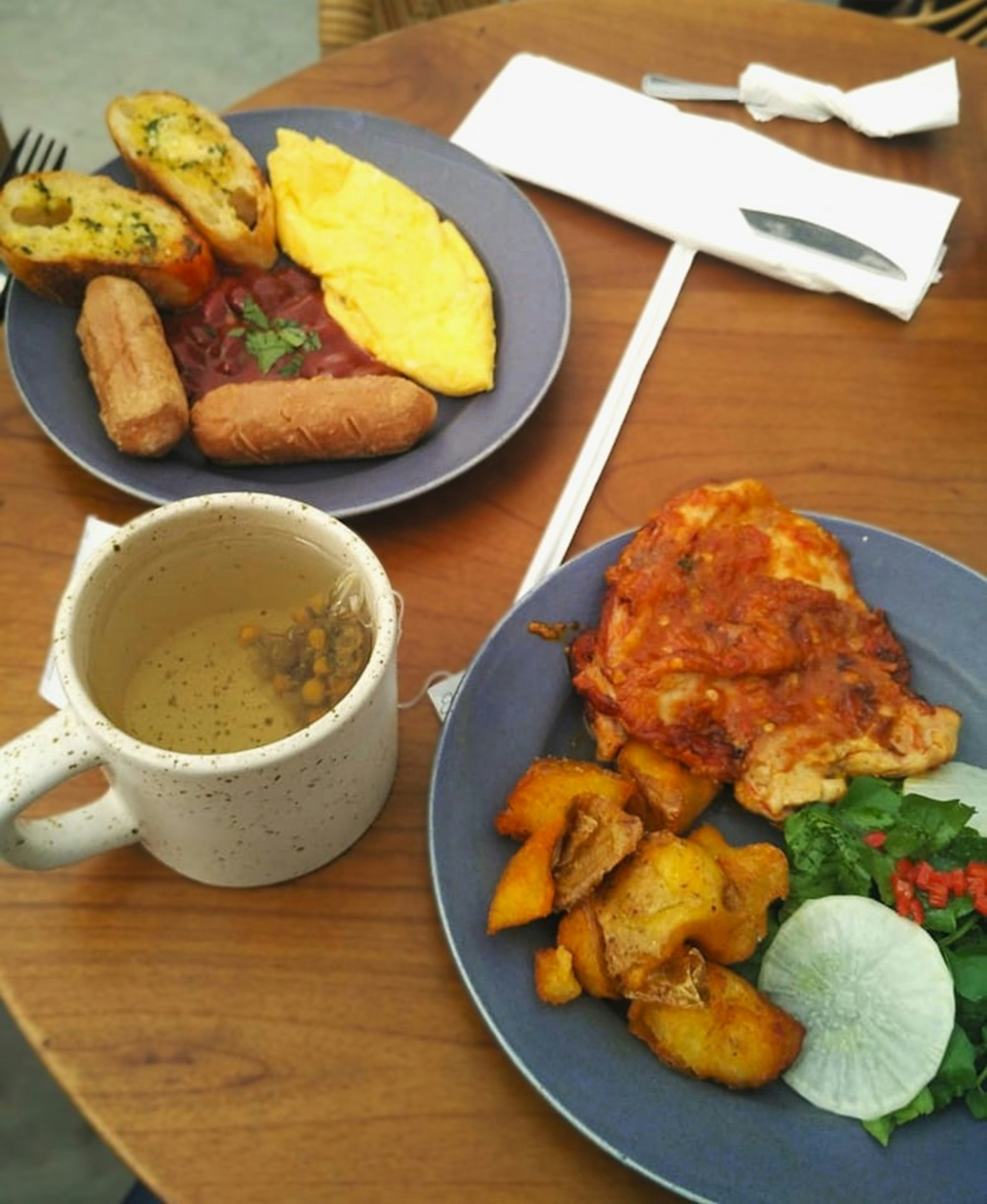A wooden table topped with plates of food and a cup of coffee