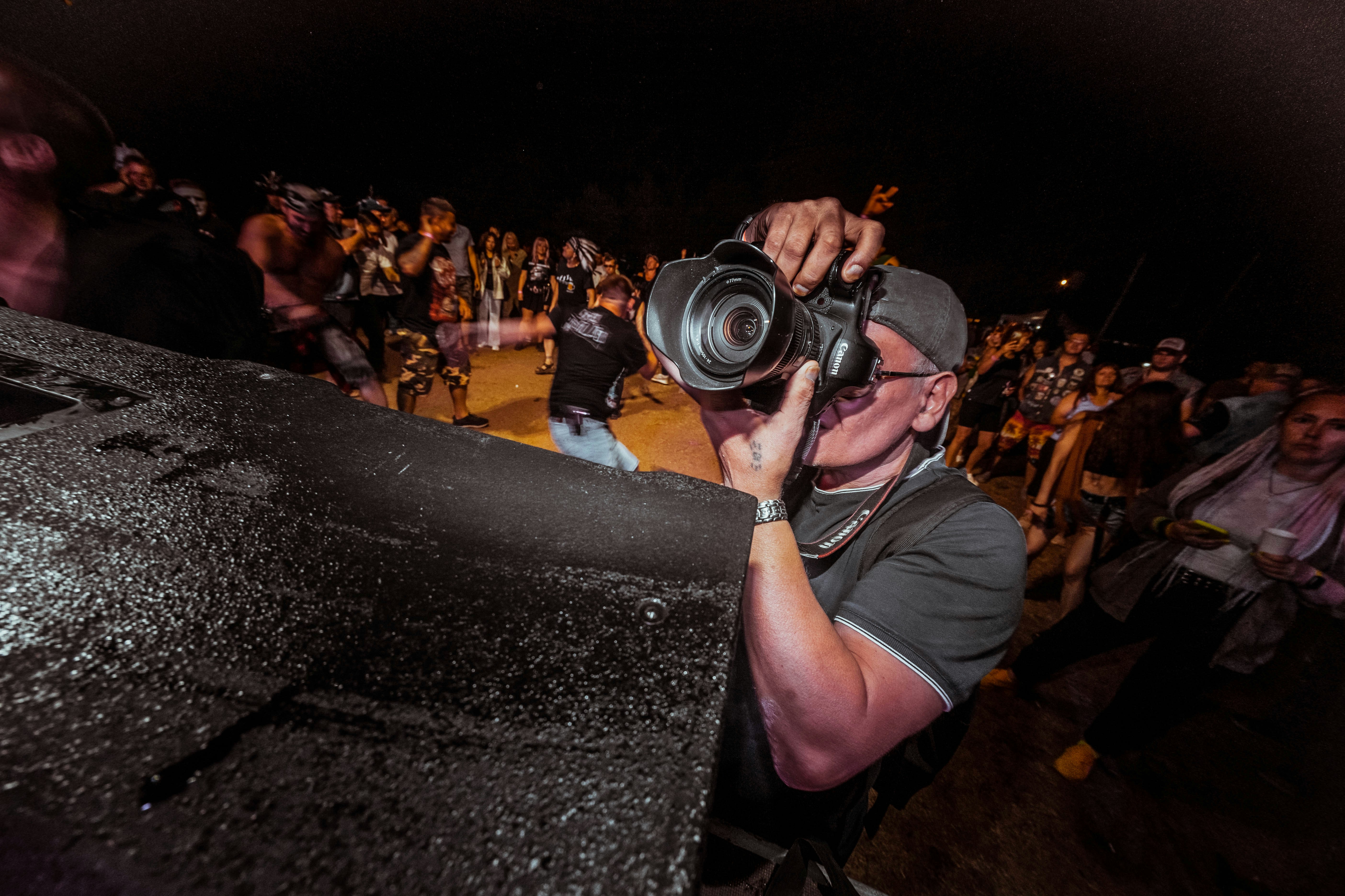 Photographer with camera at an outdoor event, bright natural light, candid moment capture, airy well-lit environment