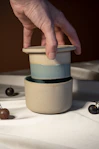 A hand reaching for a cup with cherries on a table