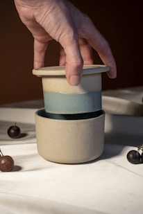 A hand reaching for a cup with cherries on a table