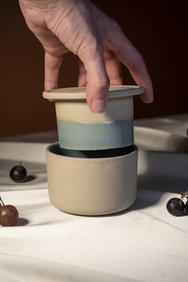 A hand reaching for a cup with cherries on a table