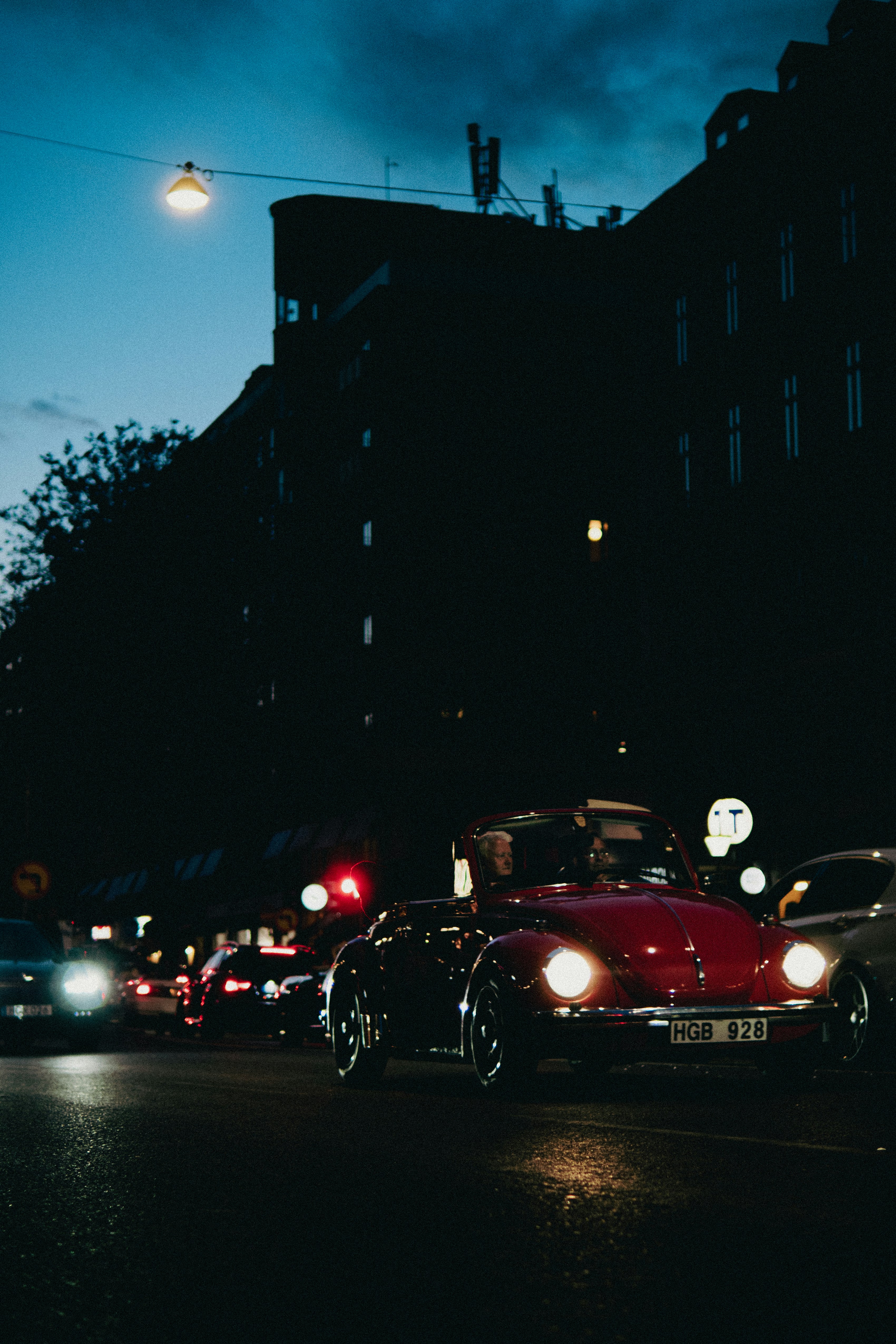 A red car driving down a street at night
