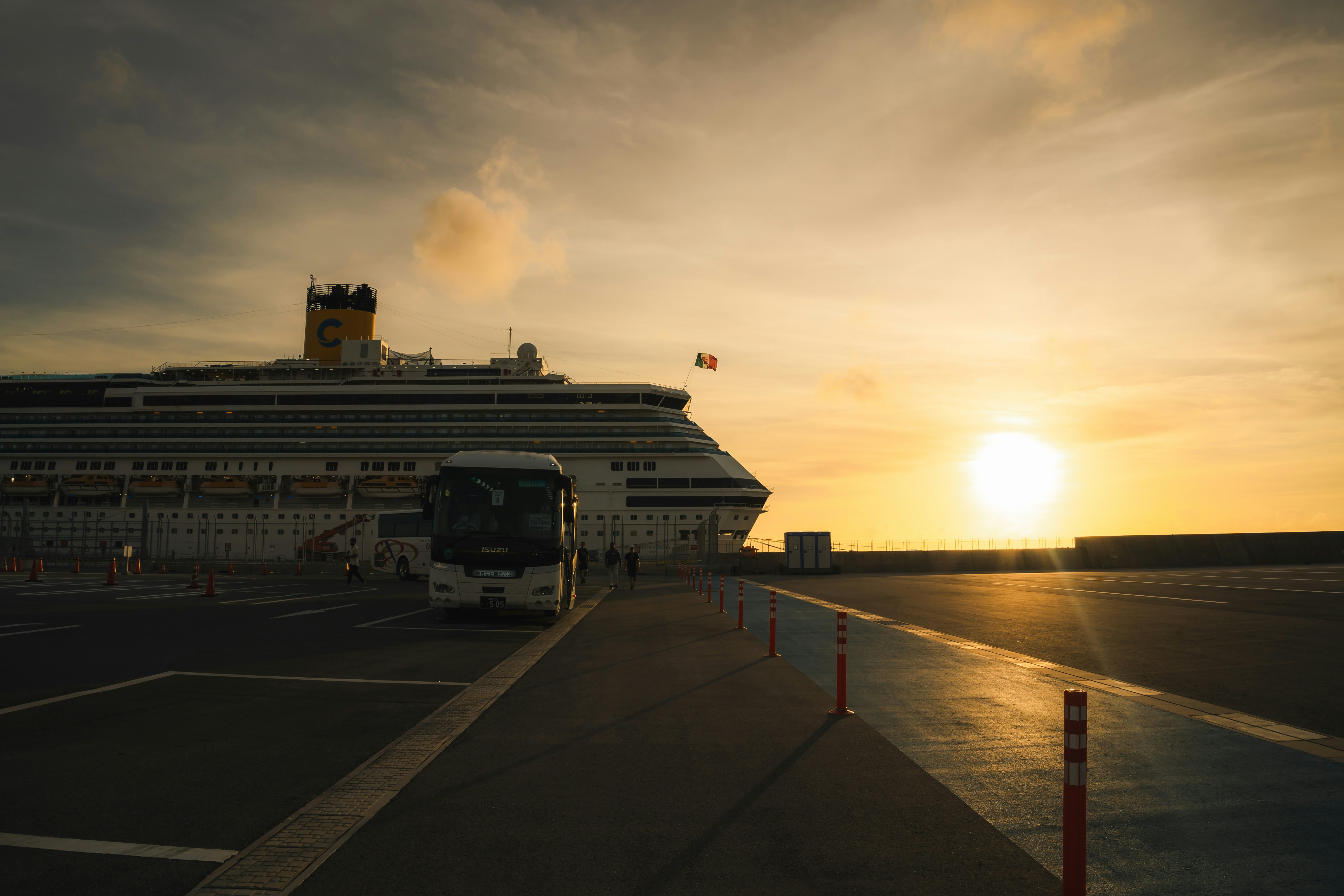 A bus parked in front of a large cruise ship, Sunset Vibe at the port with Cruise Ship in Naha, Okinawa, Japan