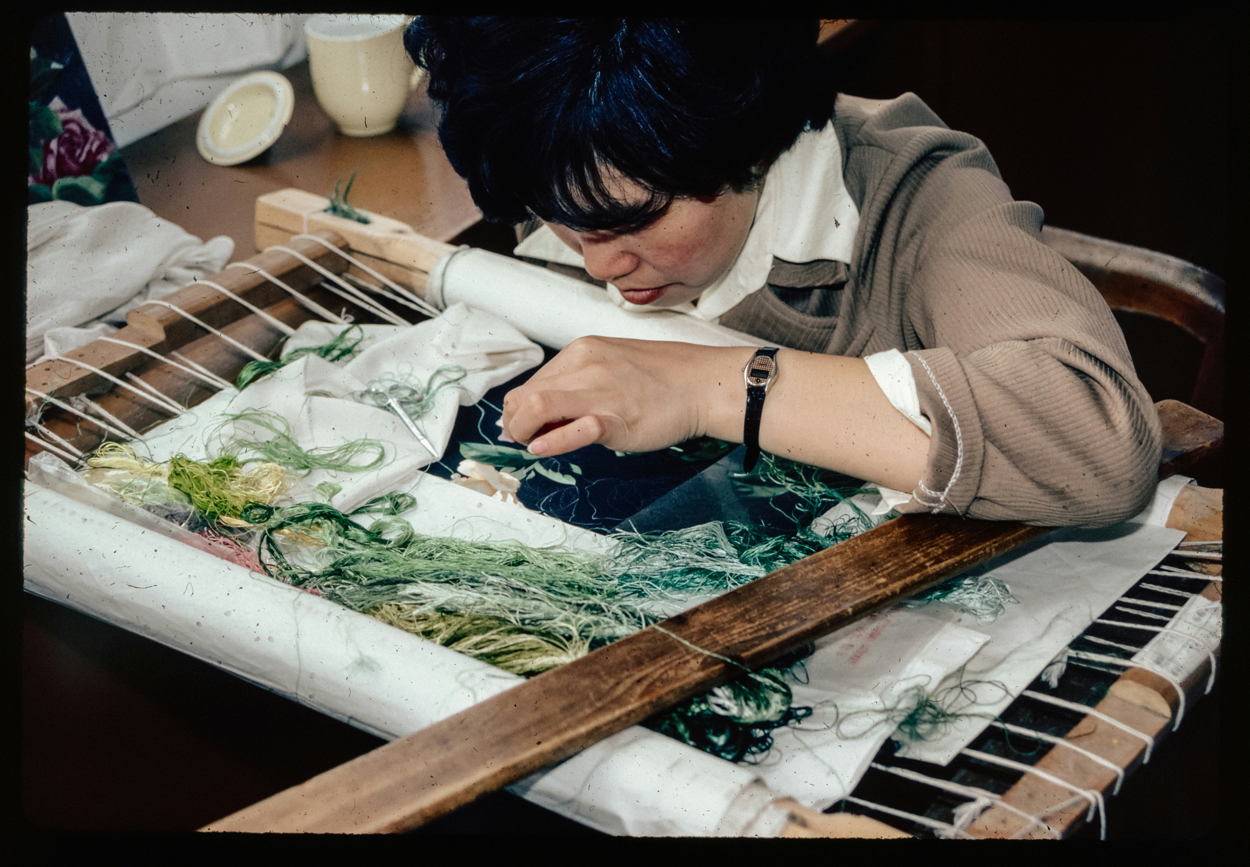 Person using a tufting gun on stretched fabric, creating a colorful tufted rug.