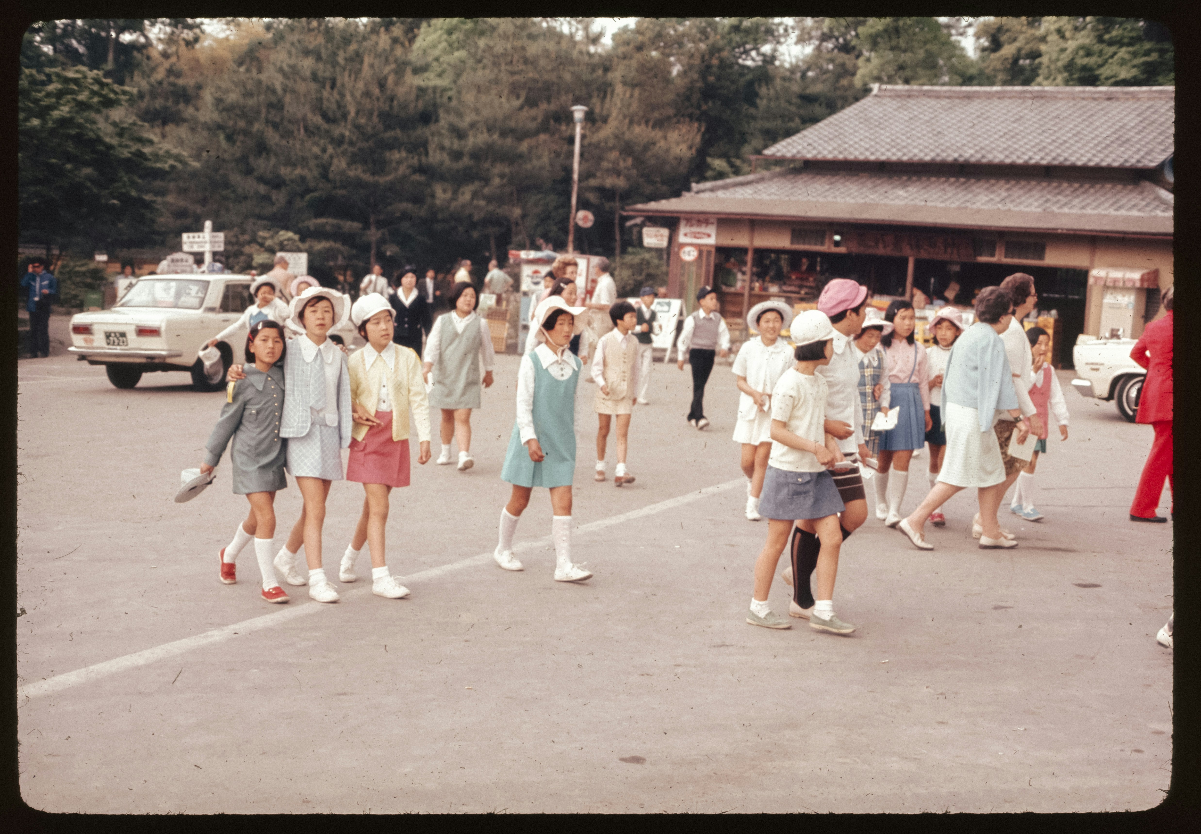 A group of people walking across a parking lot