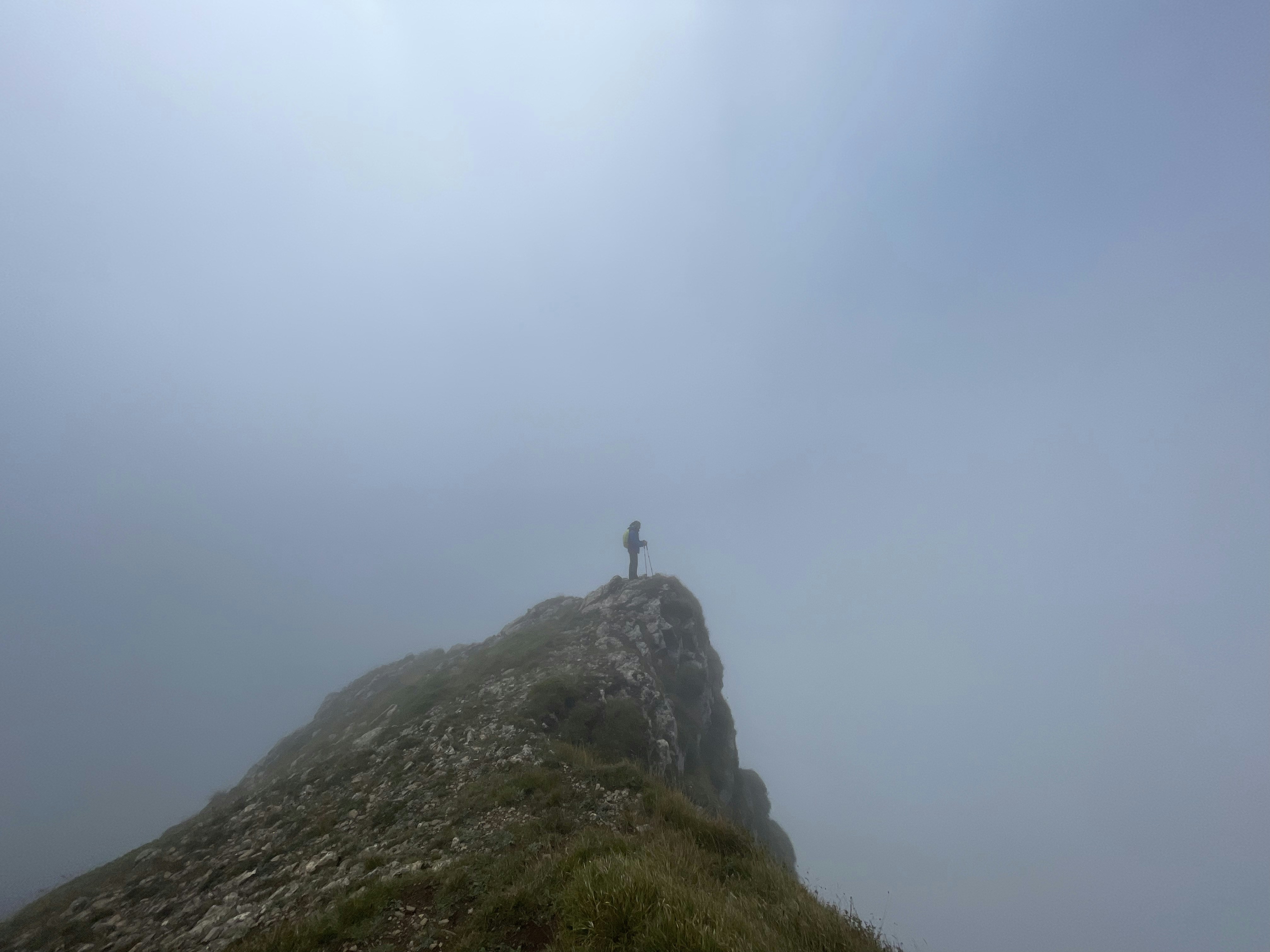 A person standing on top of a mountain on a foggy day