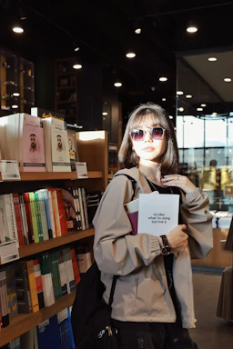 A woman standing in front of a bookshelf holding a book