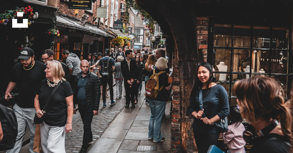 A group of people walking down a street next to tall buildings photo ...