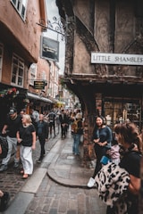A group of people walking down a street next to tall buildings