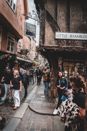 A group of people walking down a street next to tall buildings