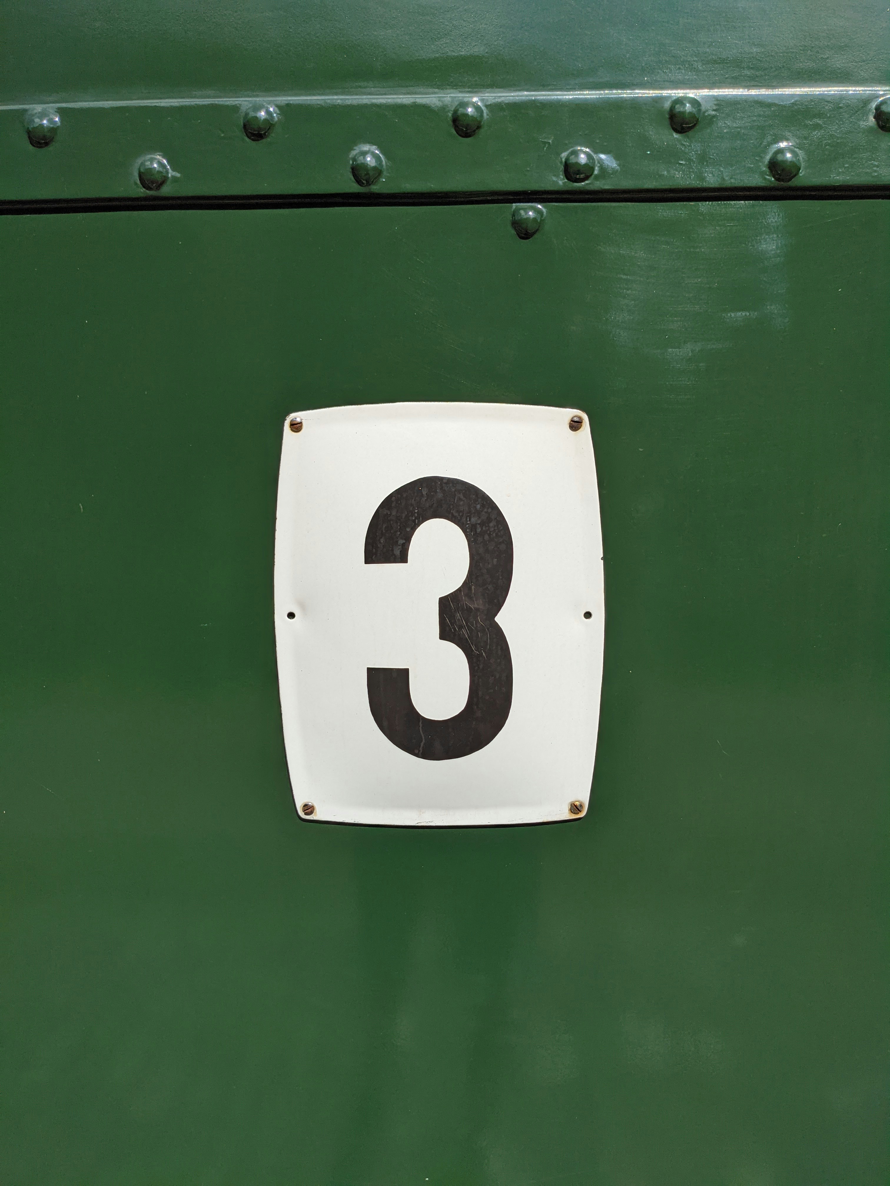 A close up of the number three on a green door