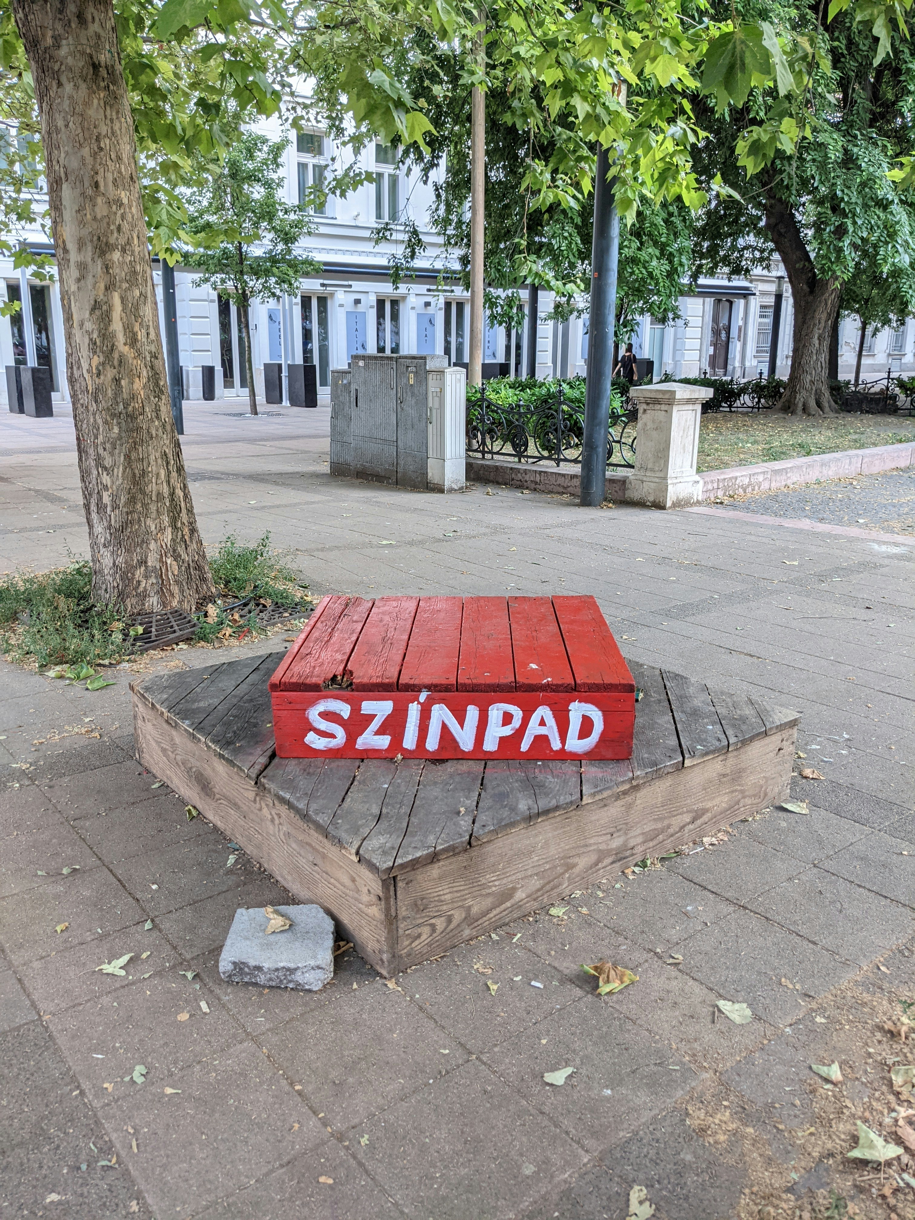 A red bench sitting on top of a sidewalk next to a tree