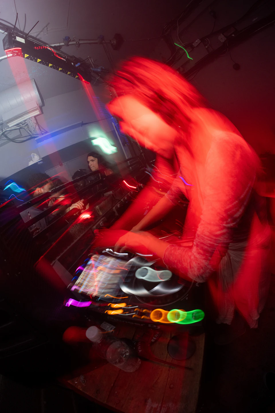 DJ works on turntable surrounded by colorful lights and equipment at music venue