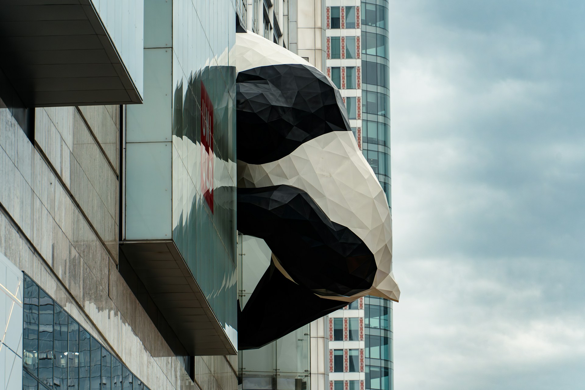 A giant panda bear sculpture hanging from the side of a building