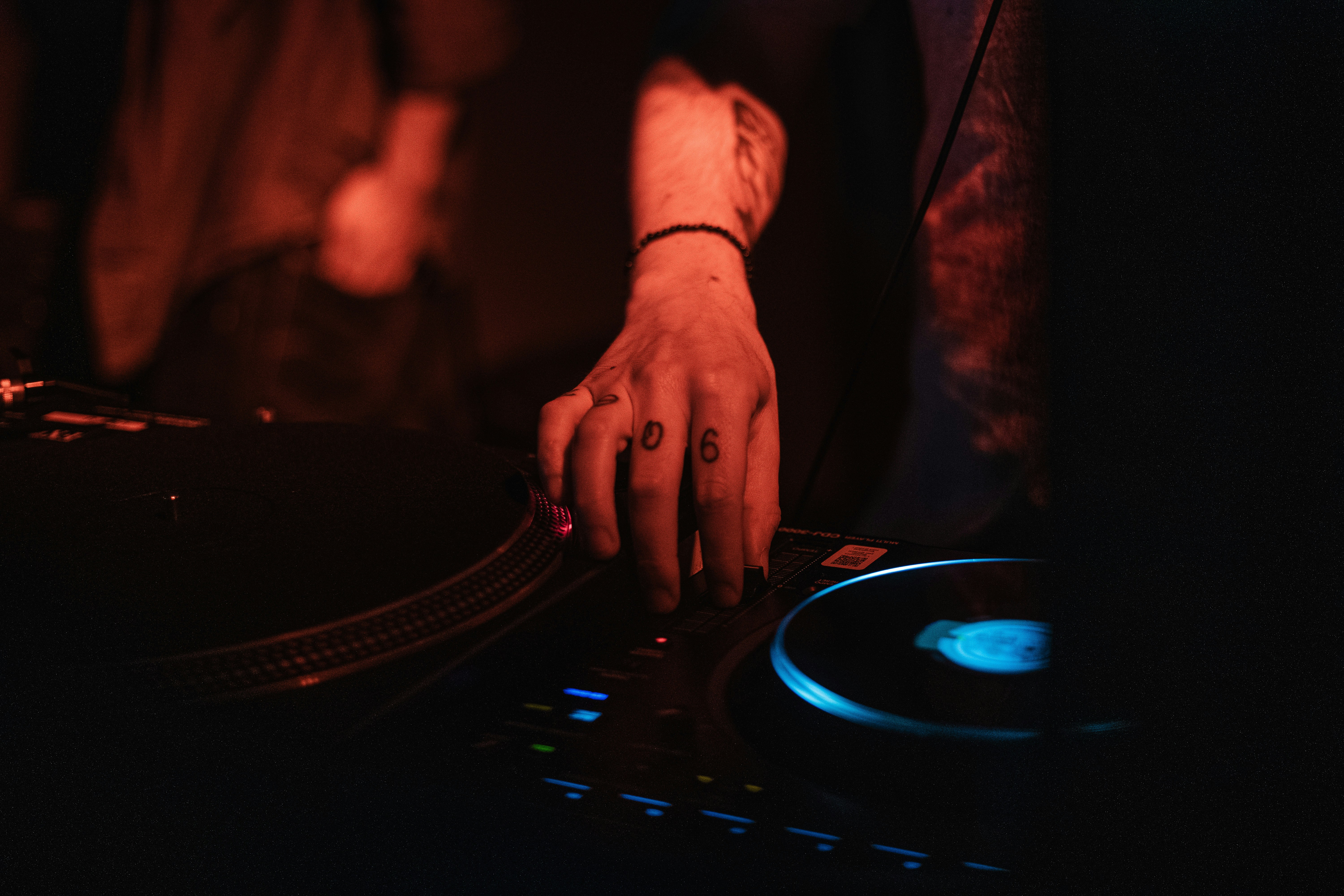 A DJ's hands on a mixer at a vibrant party