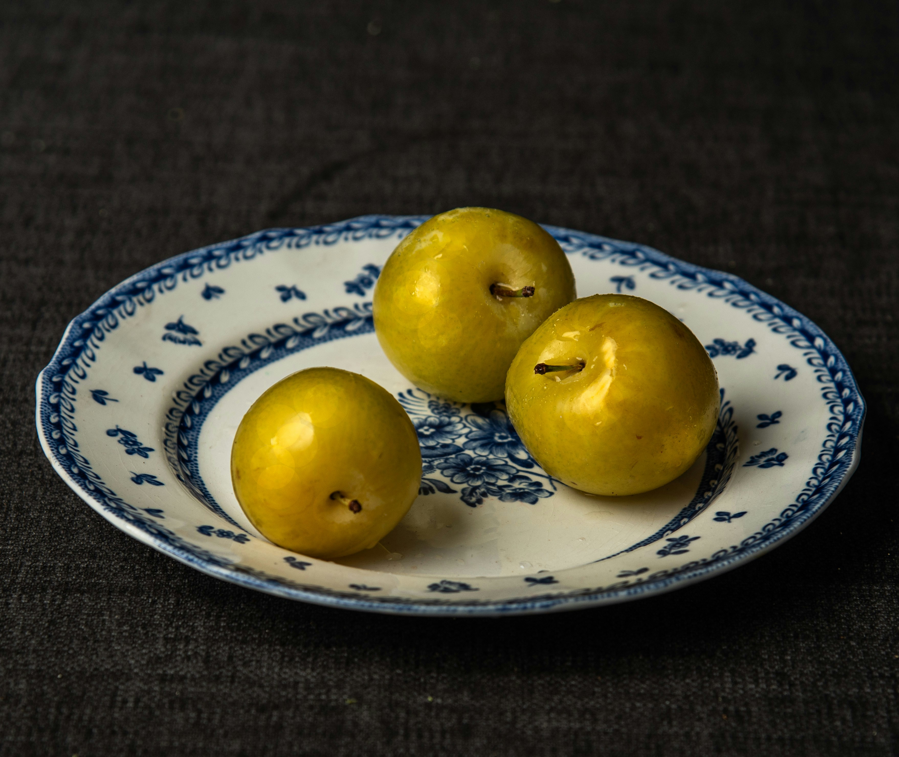 Three apples are sitting on a blue and white plate