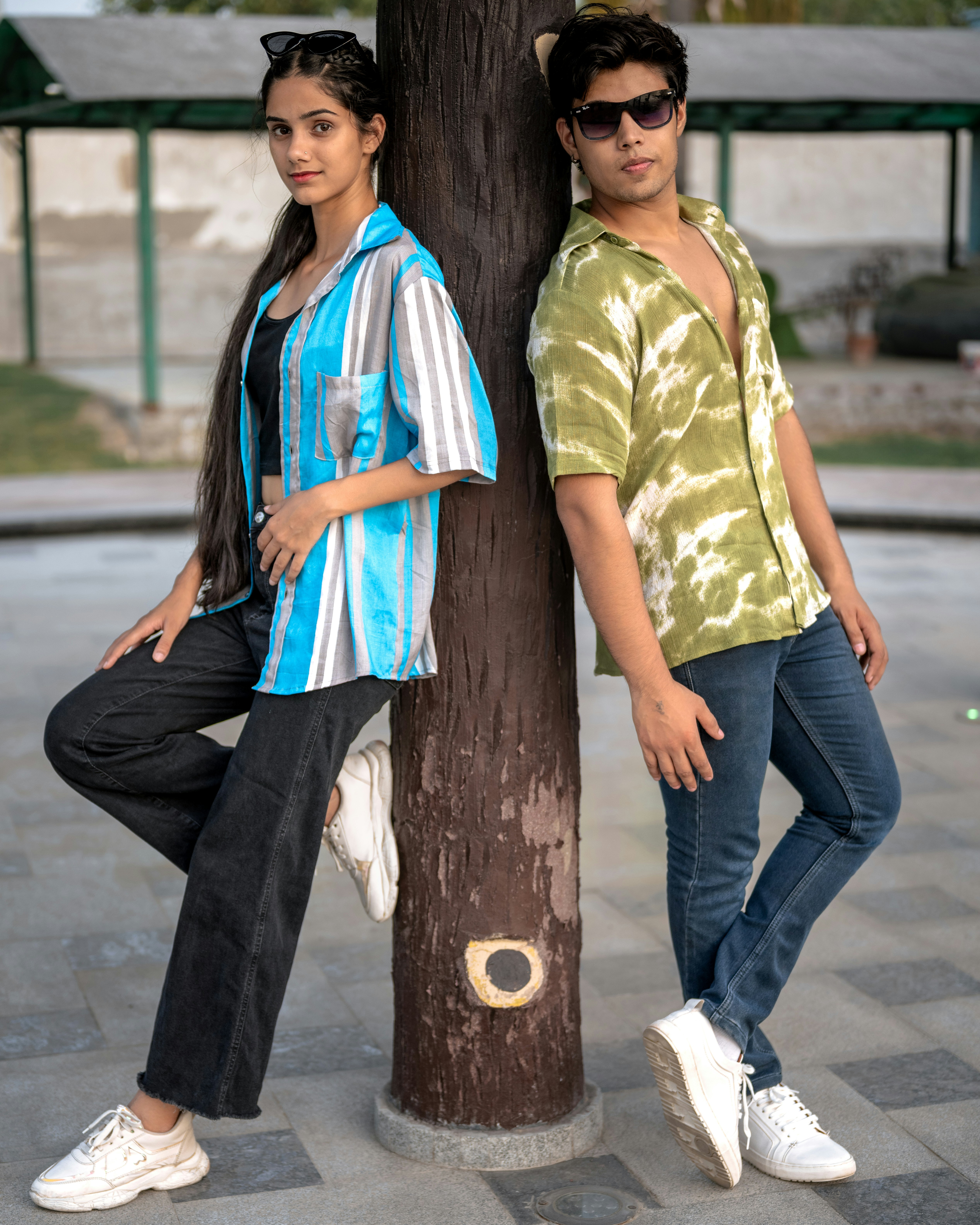 A couple of people standing next to a tree